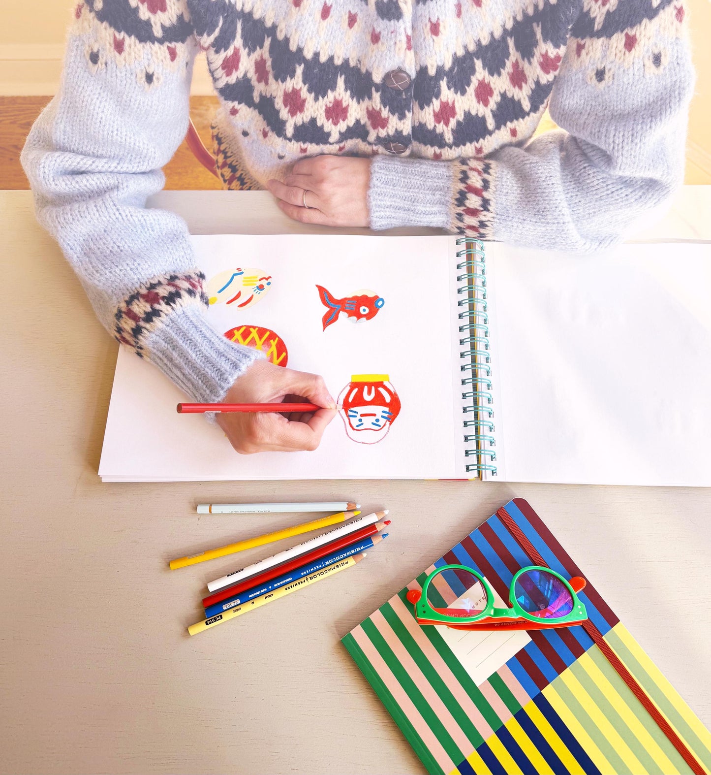 Person coloring in a book with colorful pencils on a wooden table