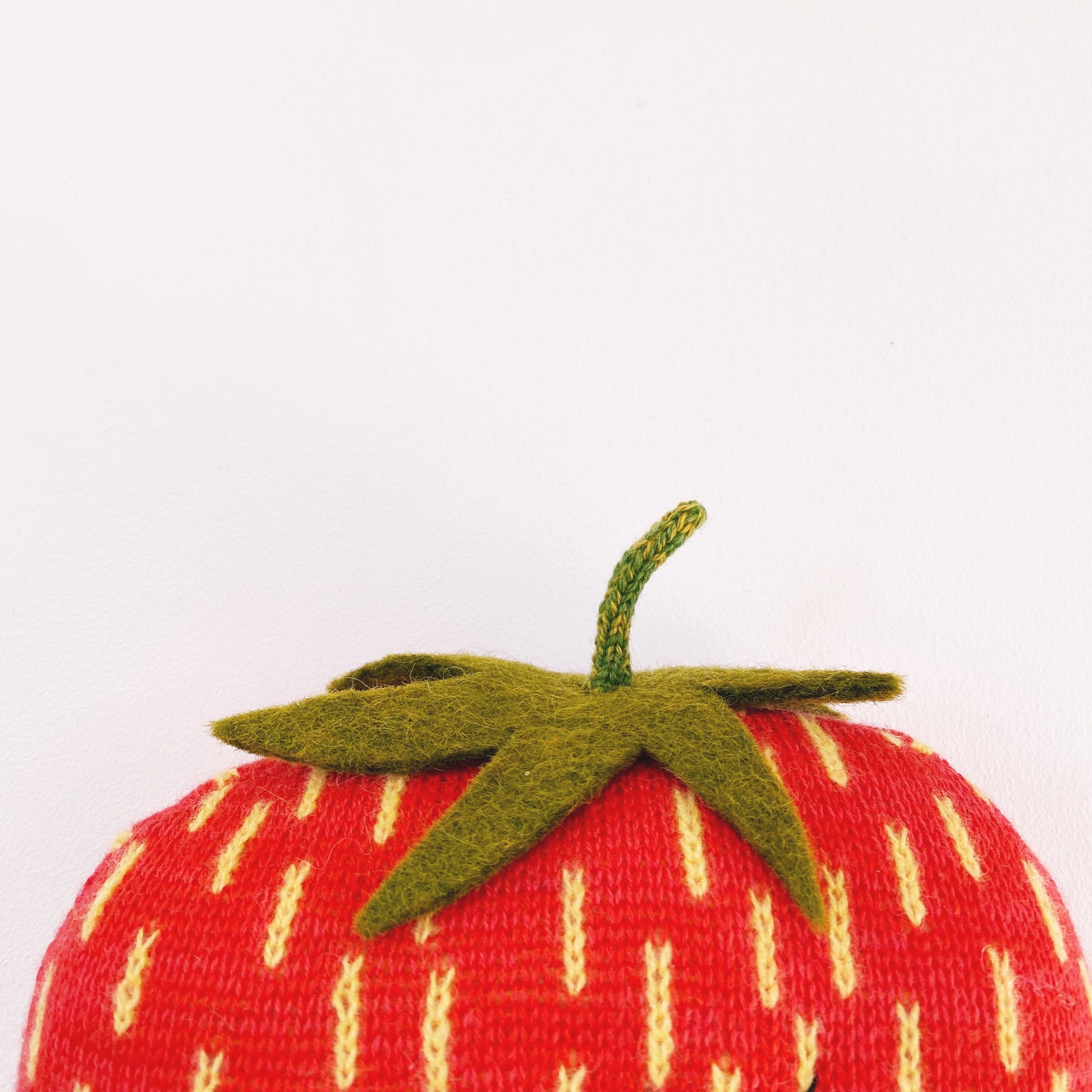 Textured red strawberry with green stem on a white background