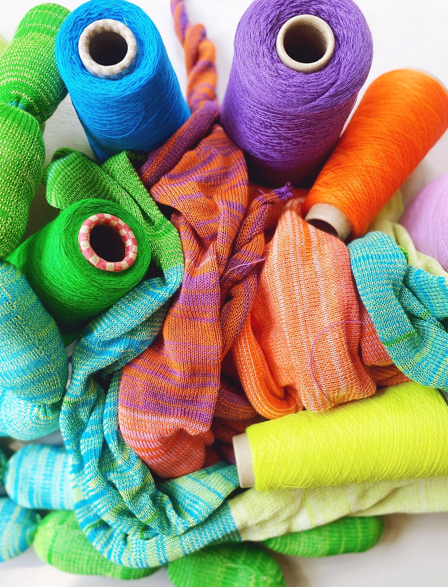 Colorful spools of yarn thread in various shades on a white background
