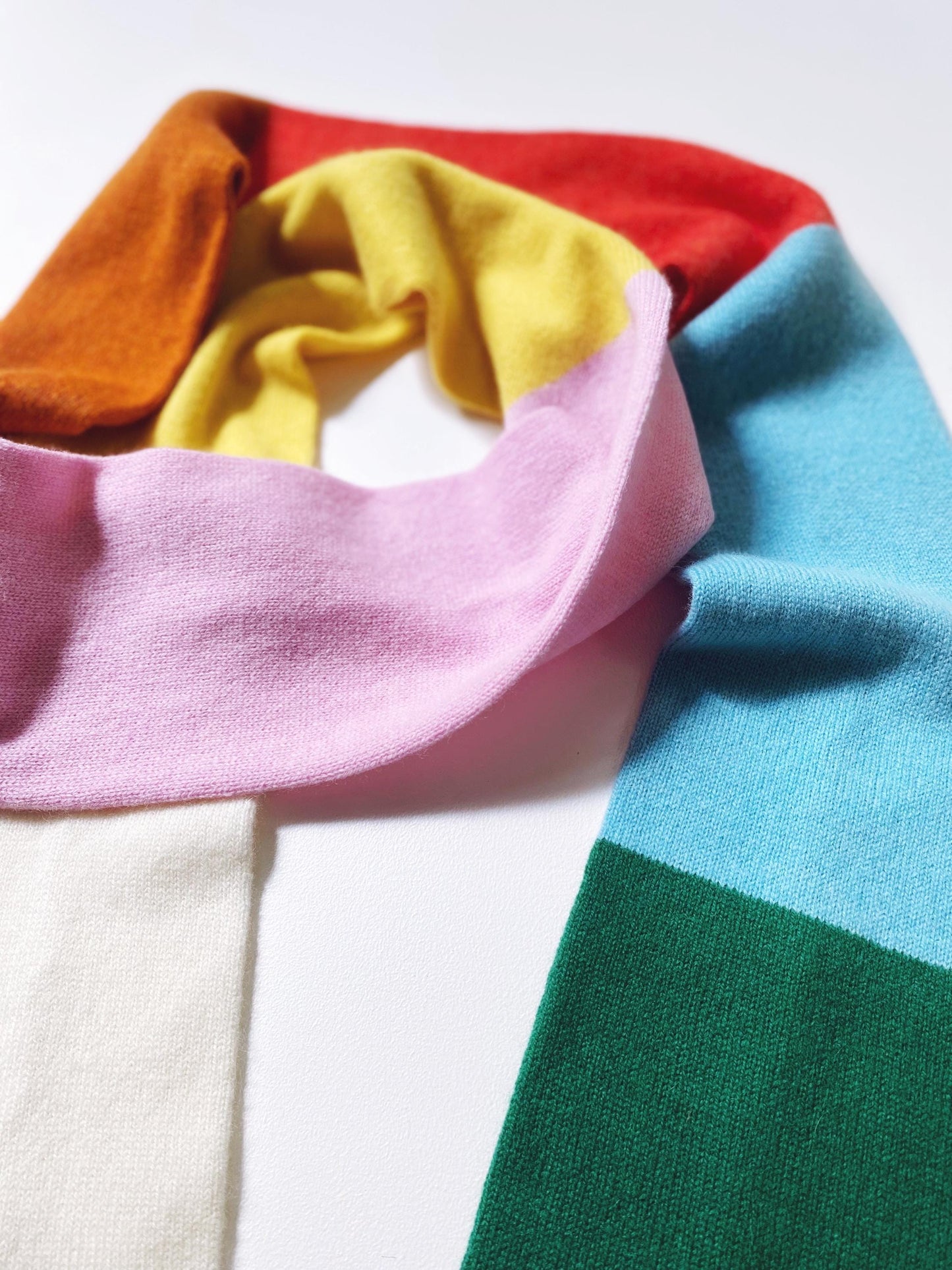 Colorful scarf with a gradient colorblock of red, orange, yellow, pink, blue, and green on a white background.