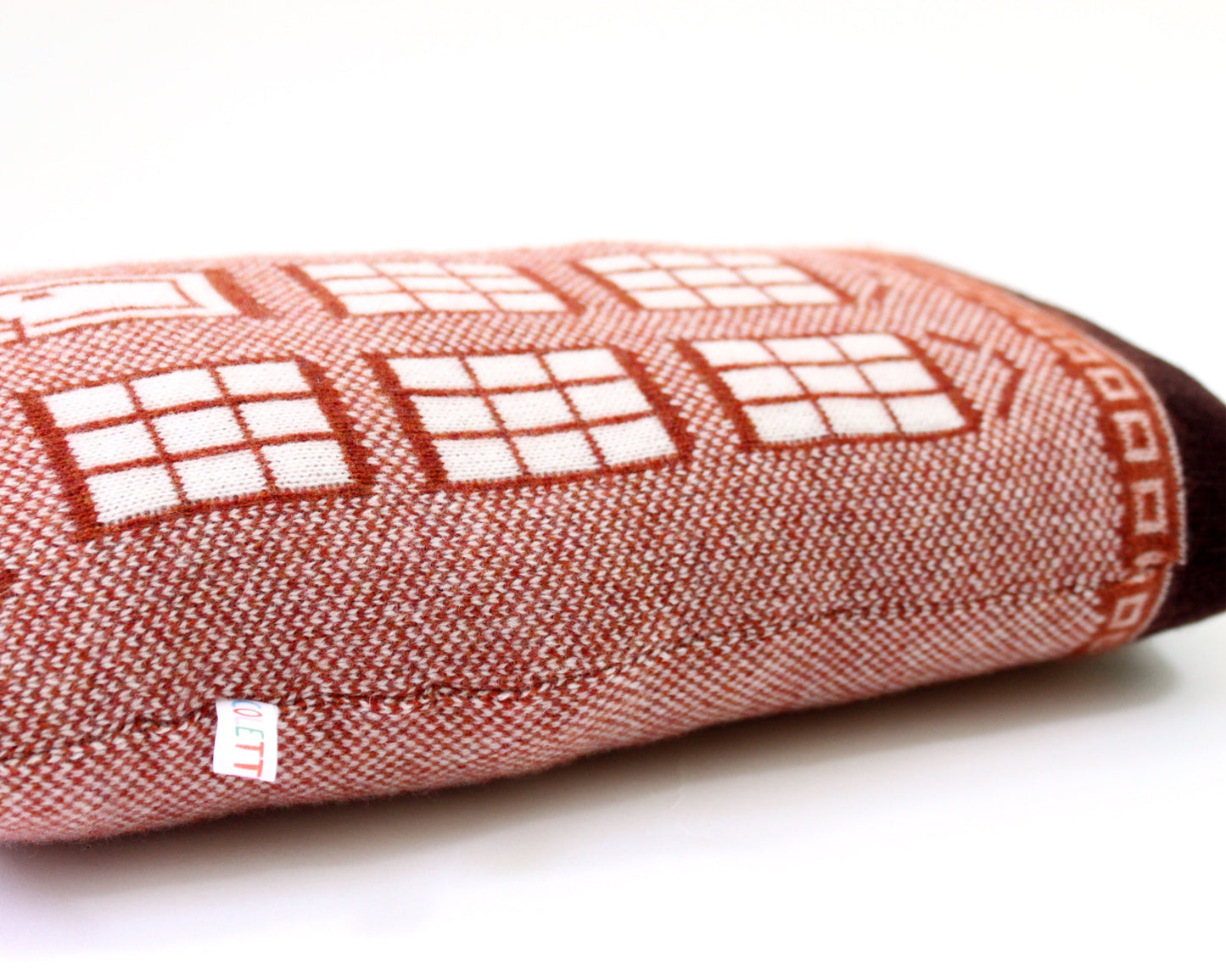 Decorative knitted pillow shaped like a house resembling a brownstone on a white background