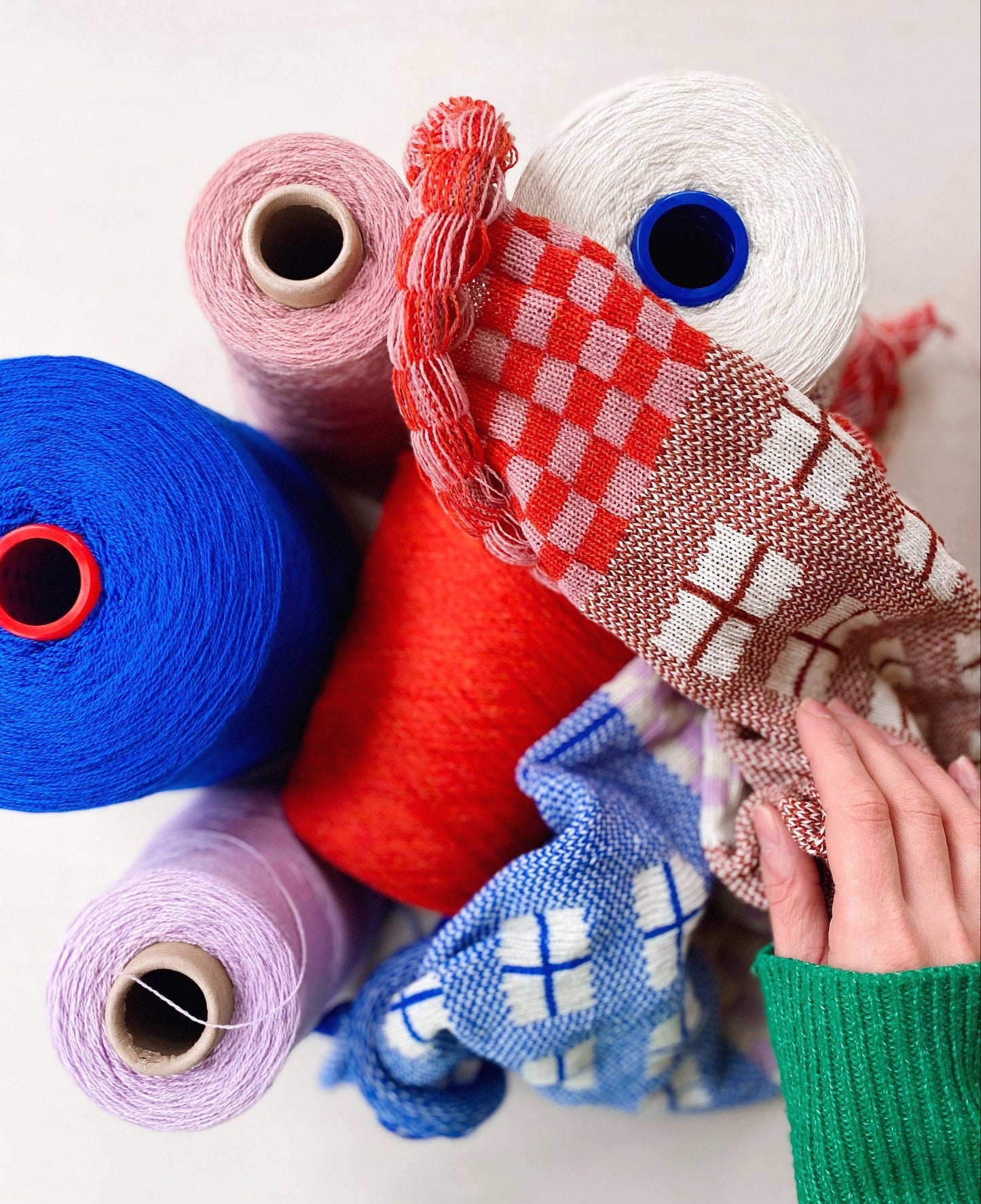 Colorful yarn rolls and fabric swatches on a white background