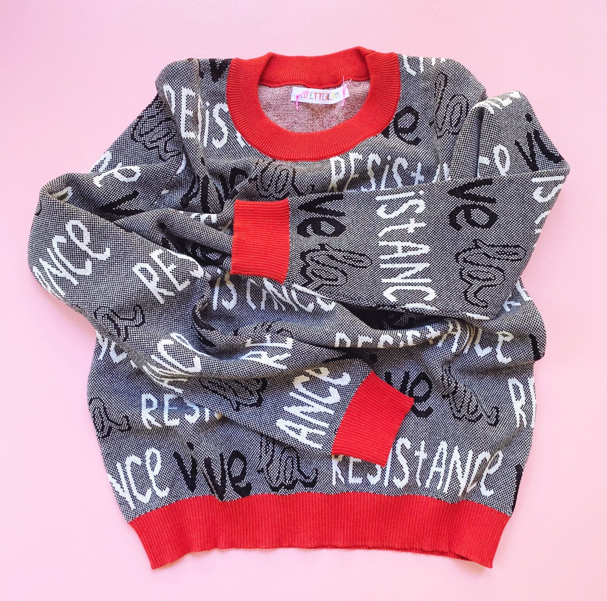 Black and white sweater with red accents and 'Vive la Resistance' text on a pink background