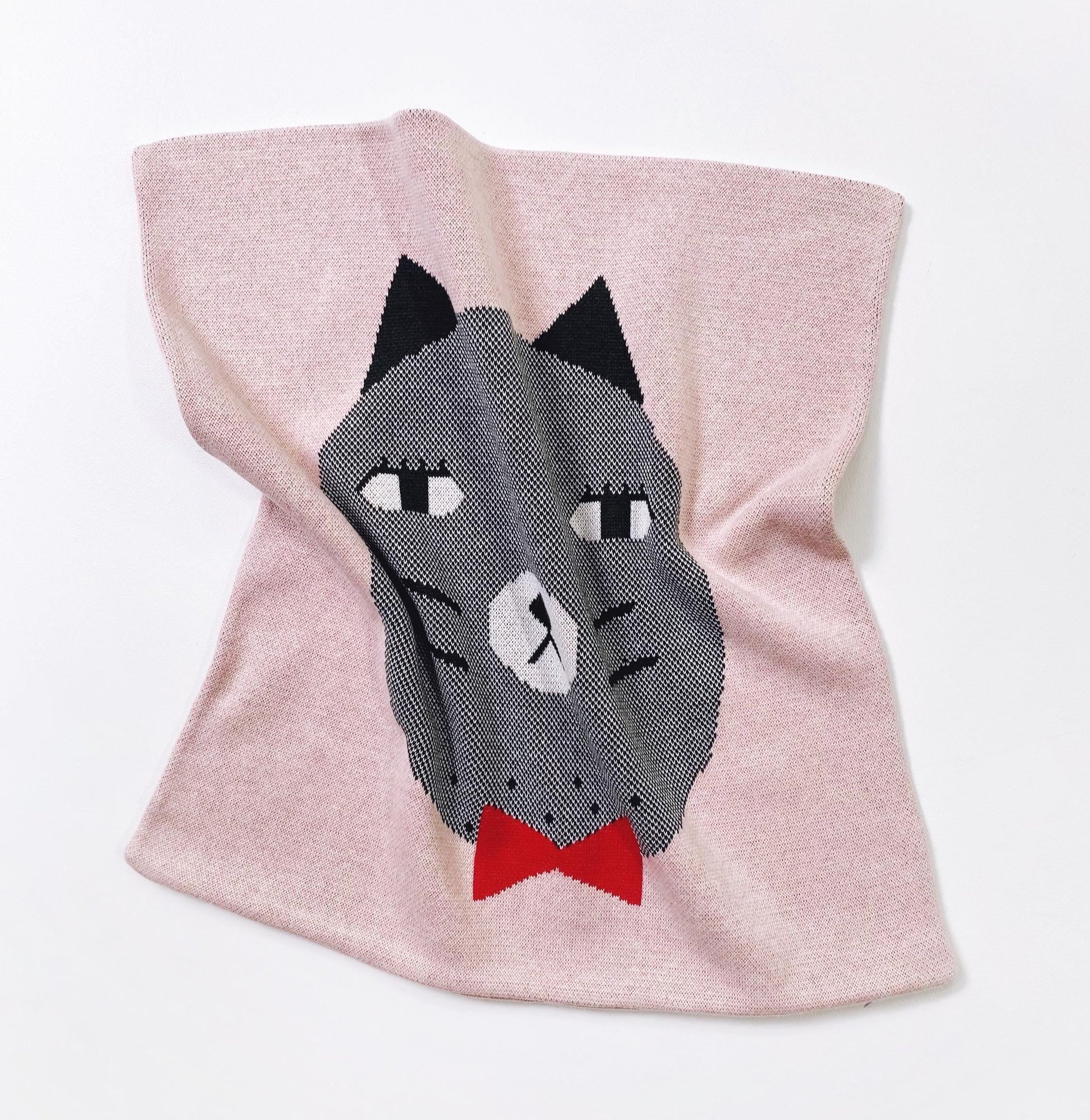 Pink knitted pillow with a cat face design on a white background