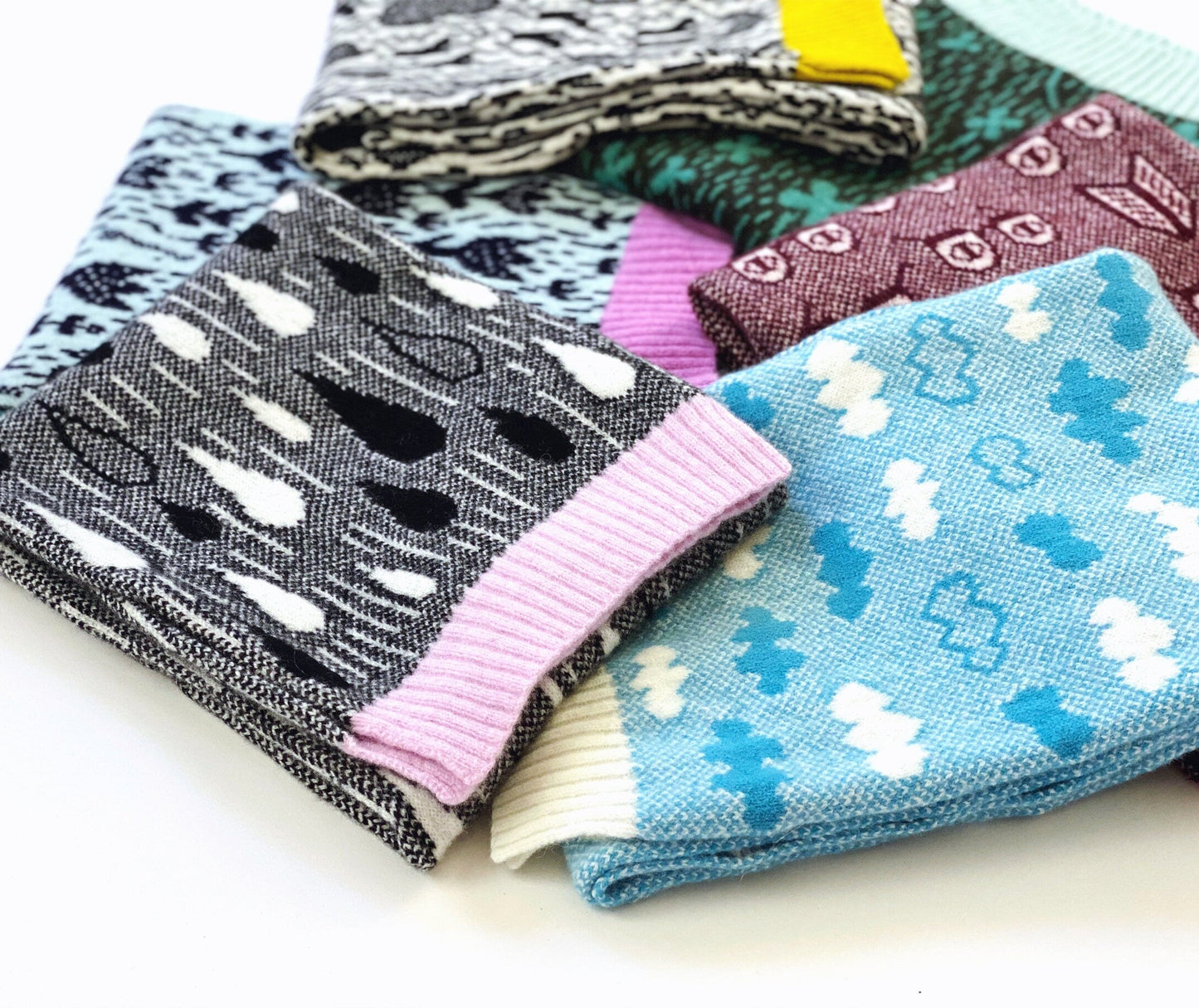 Folded colorful patterned knitted scarves on a white background