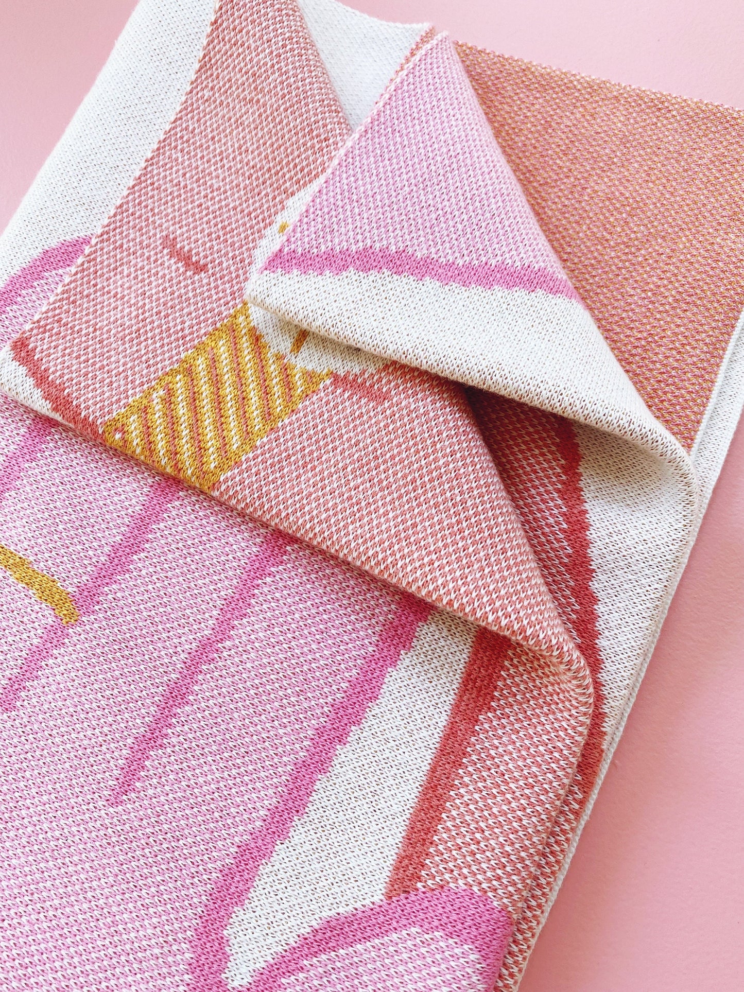 Close-up of pink and white patterned knit fabric on a pink background