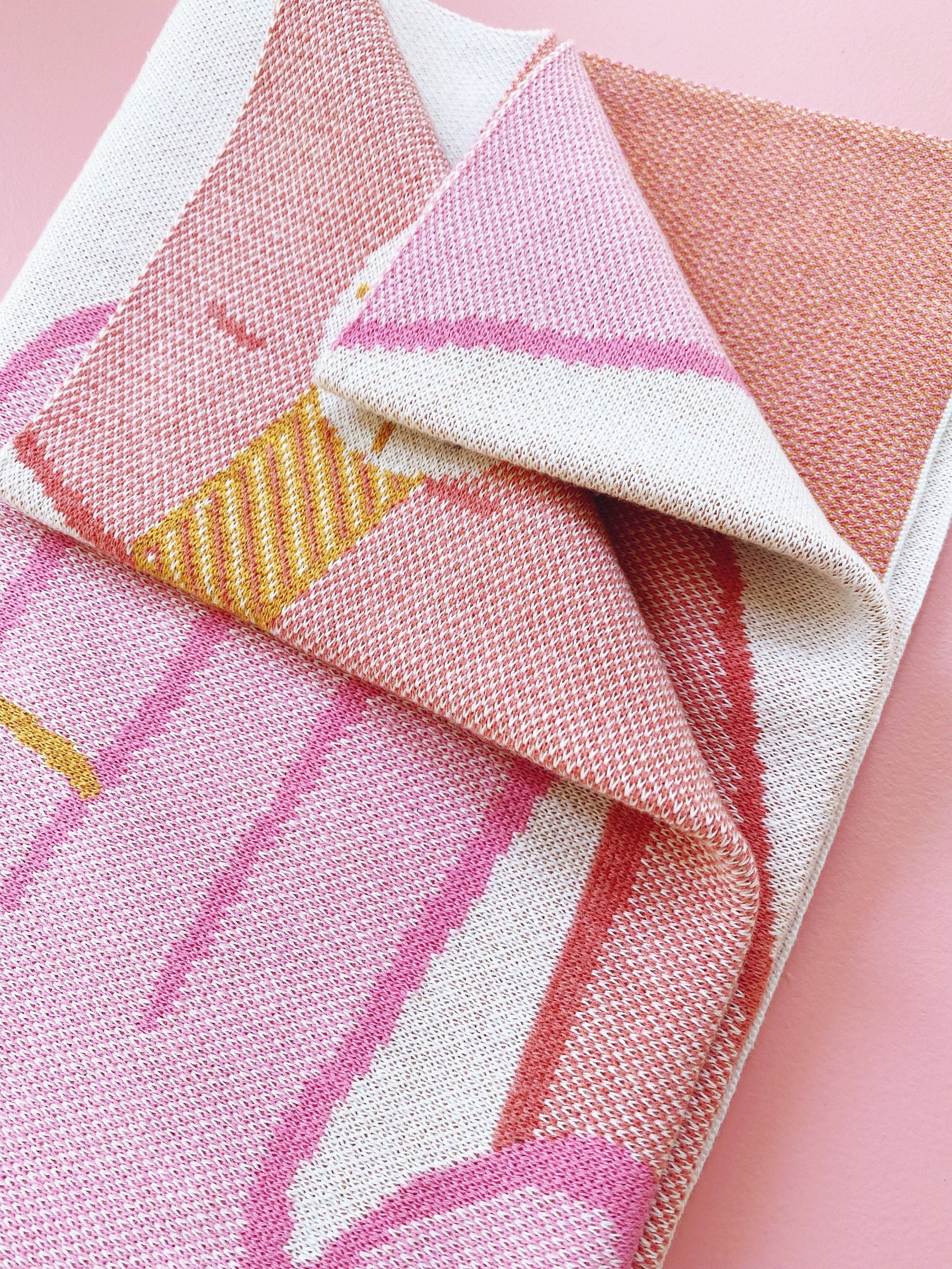 Close-up of pink and white patterned knit fabric on a pink background