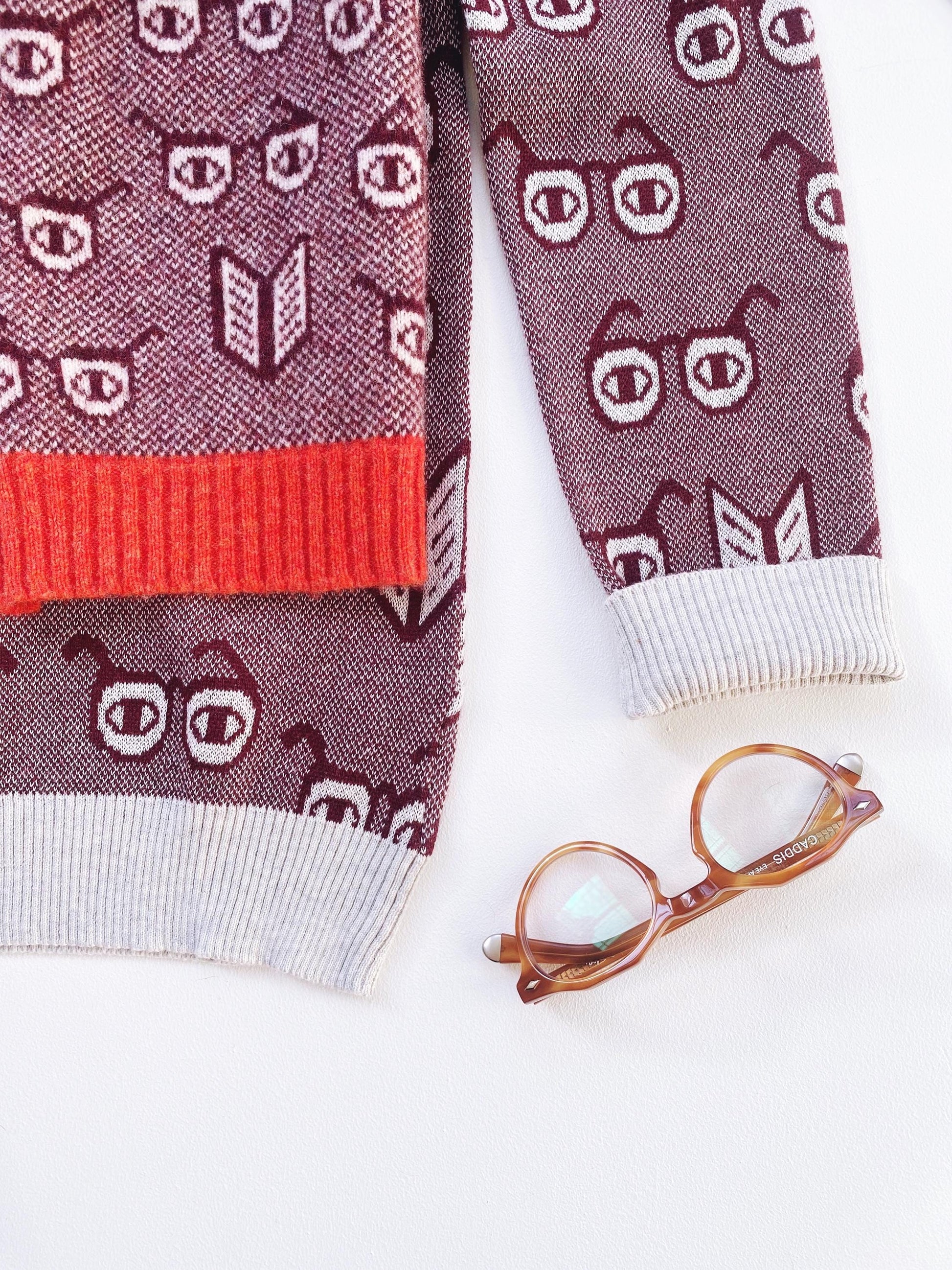 Sweater with spectacles eyeglasses themed pattern and a pair of glasses on a white background