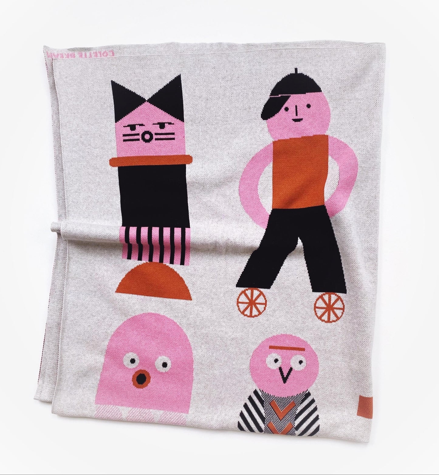 Folded knitted blanket with colorful character designs on a white background
