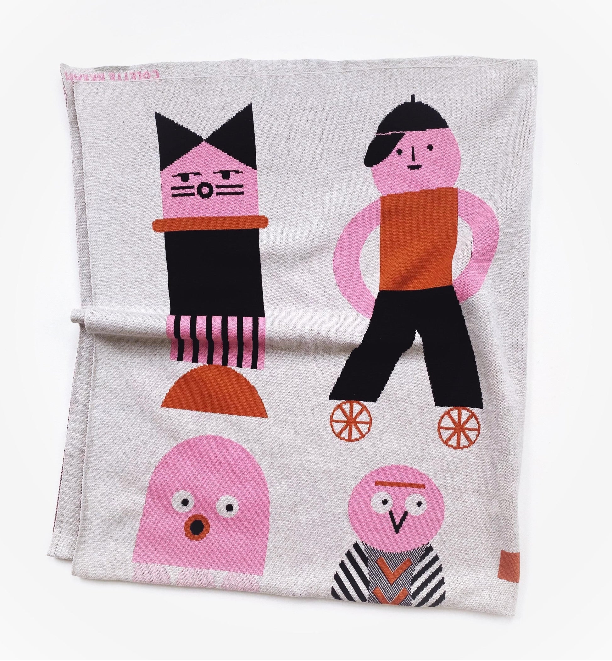 Folded knitted blanket with colorful character designs on a white background