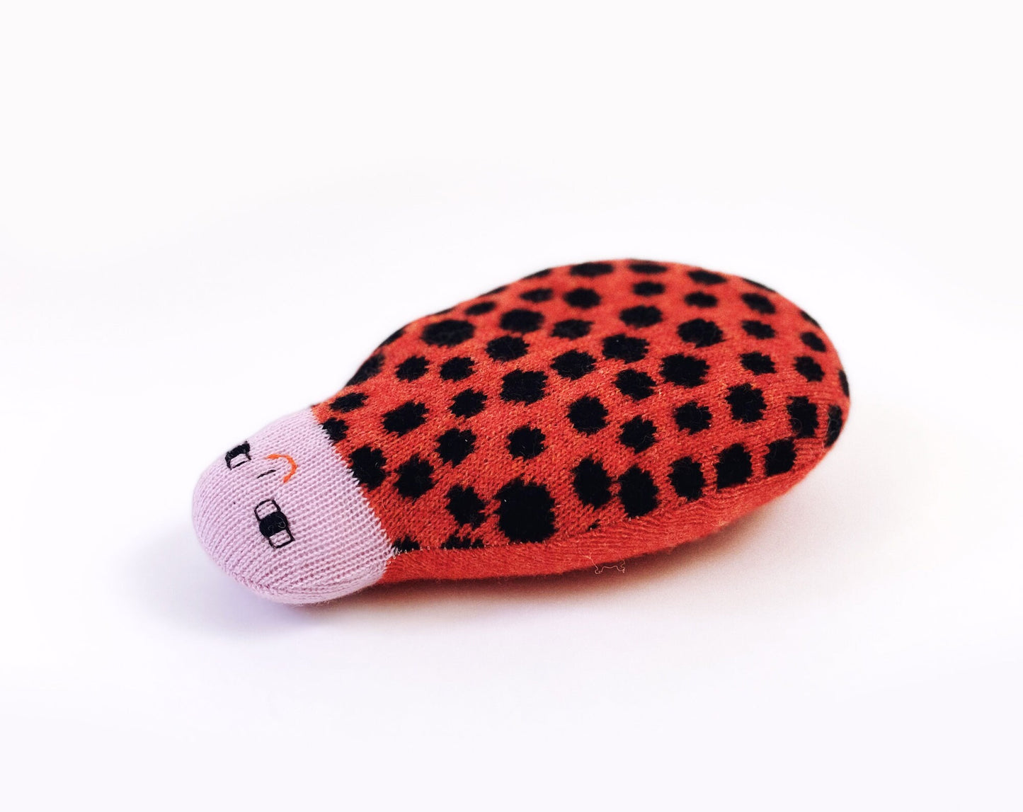 Red ladybug-shaped toy with black spots on a white background