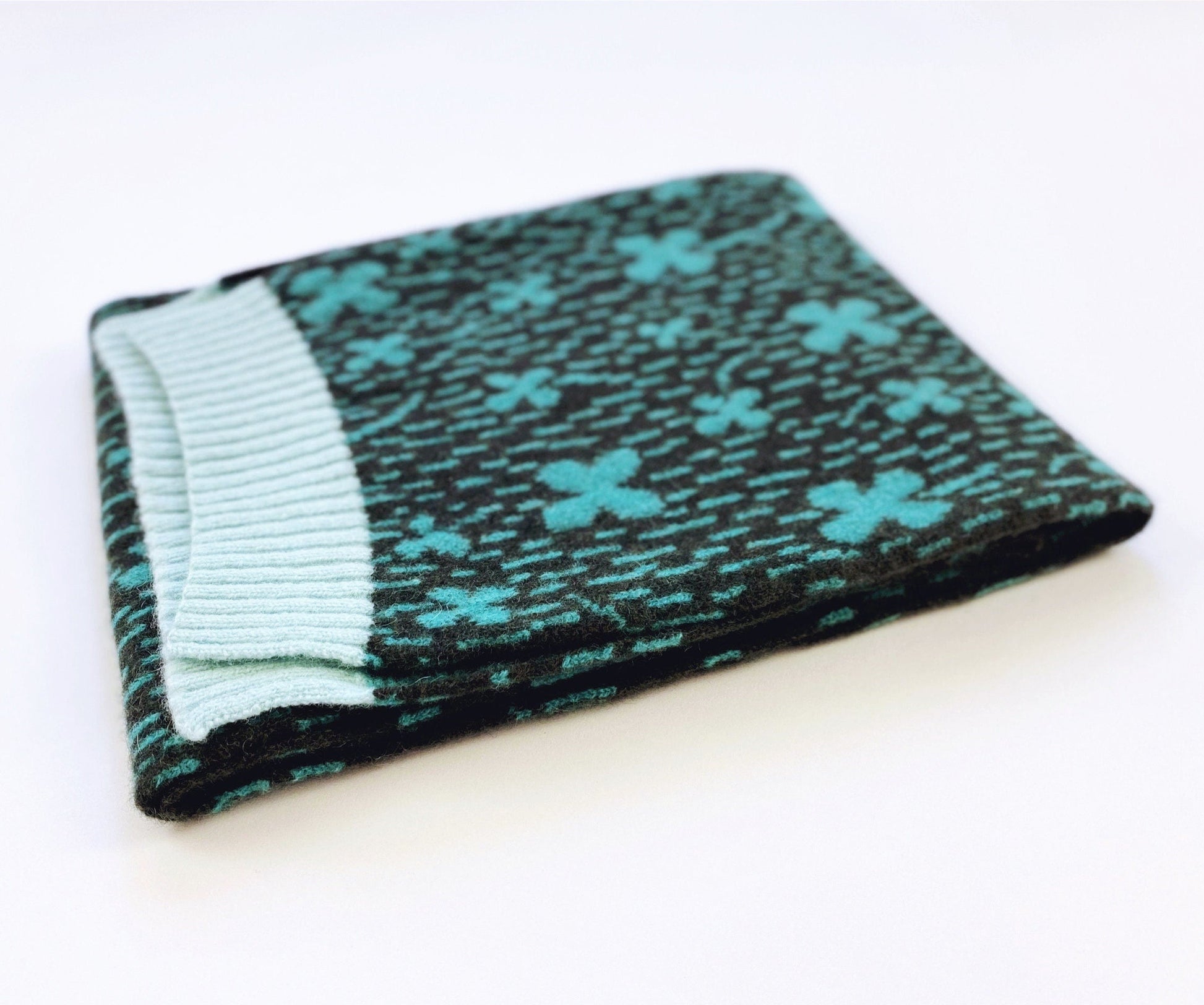 Folded lambswool knit scarf with blue floral pattern on a white background