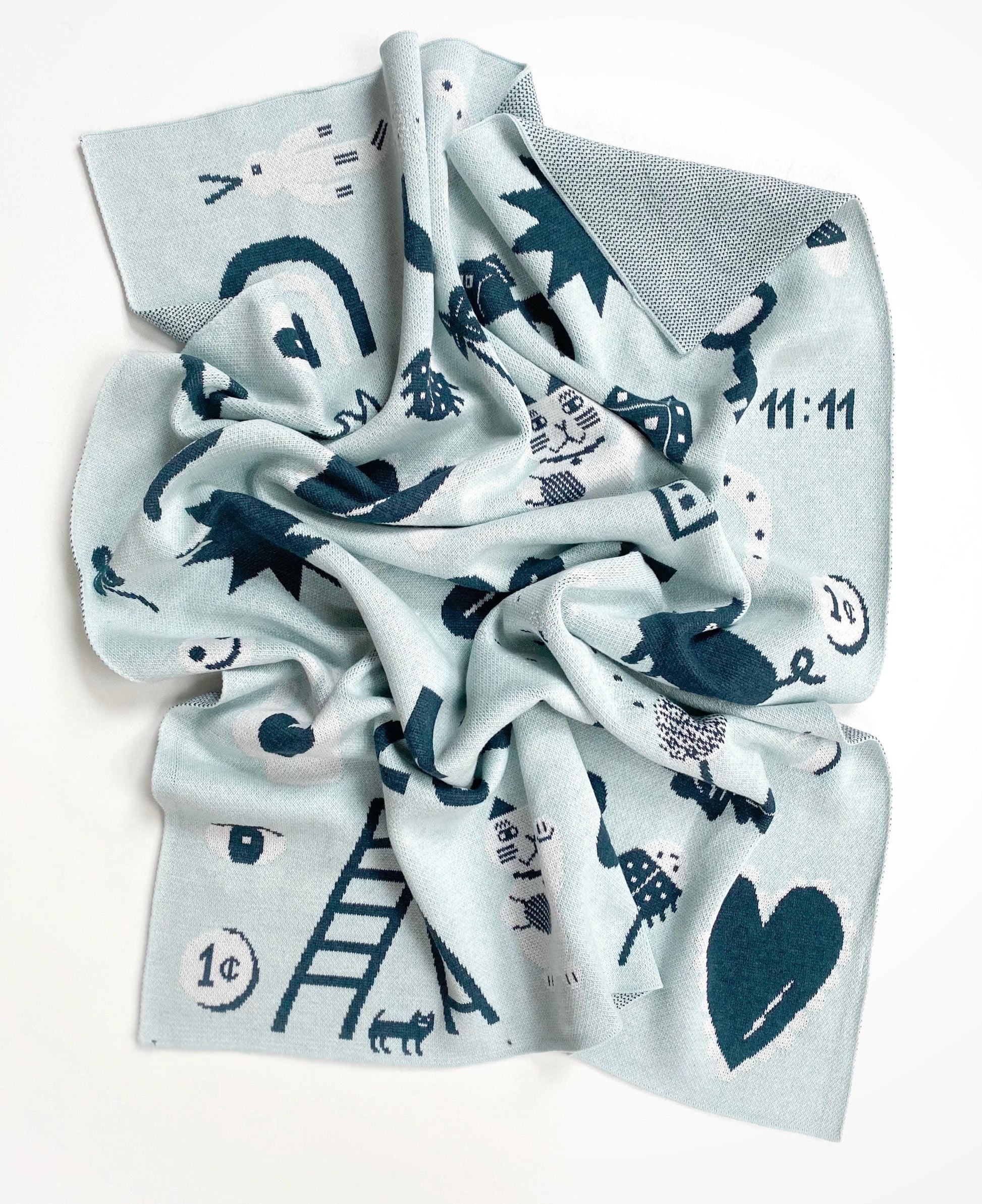 Folded knit baby blanket with blue and black good luck charm patterns on a white background