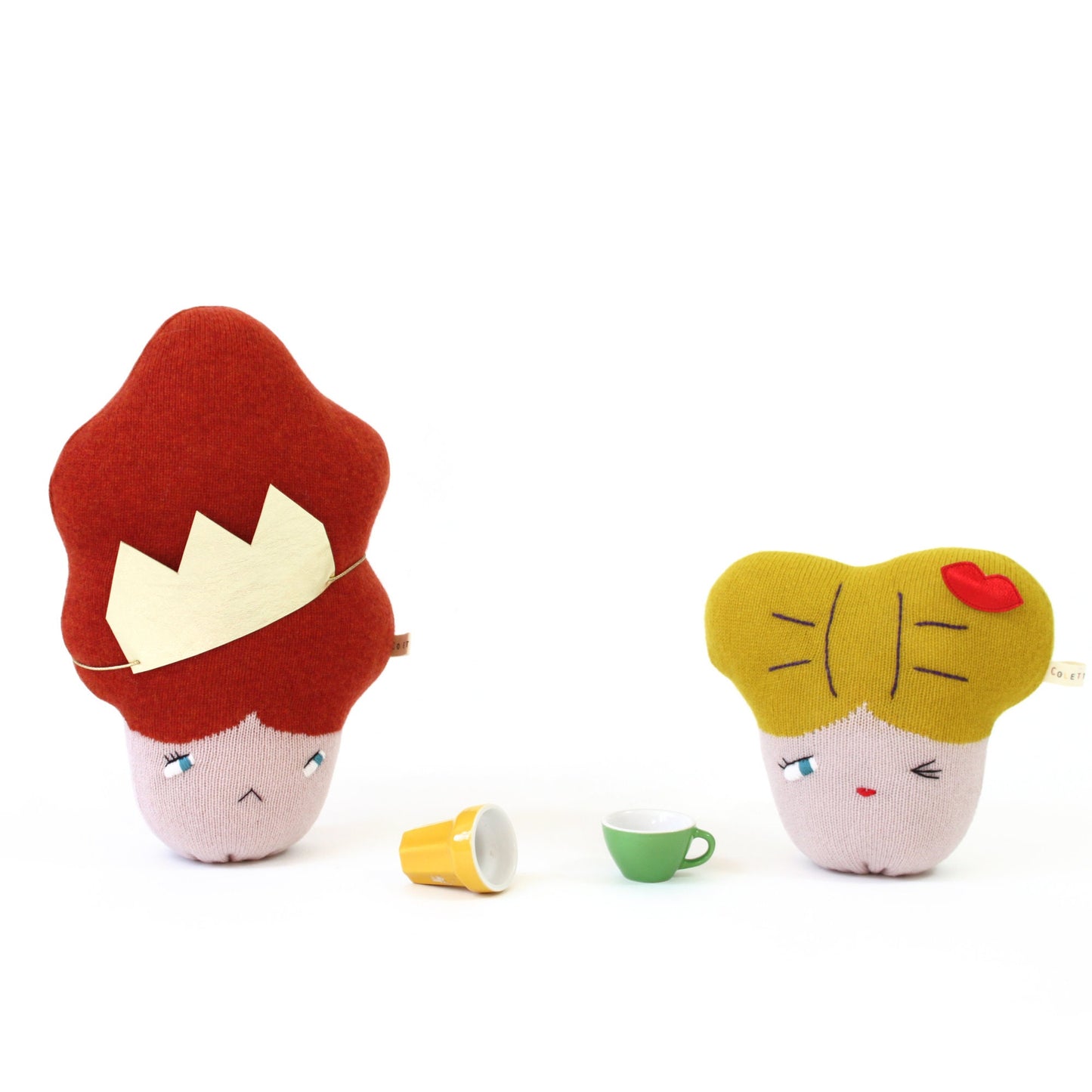 Two lambswool knitted plush toys with different hairstyles and faces on a white background