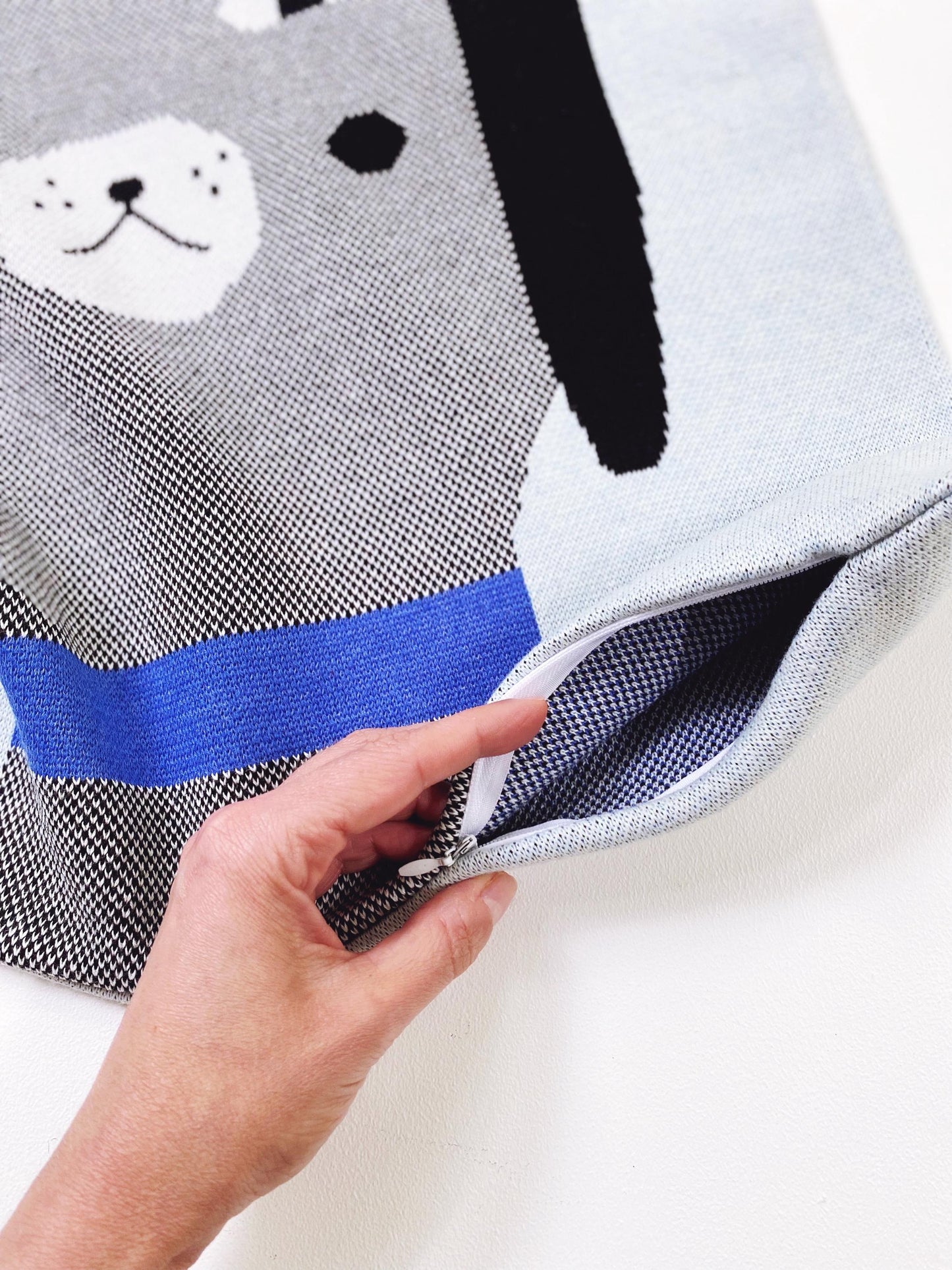 Person holding a pillow case showing a zipper closure with a dog design on a white background