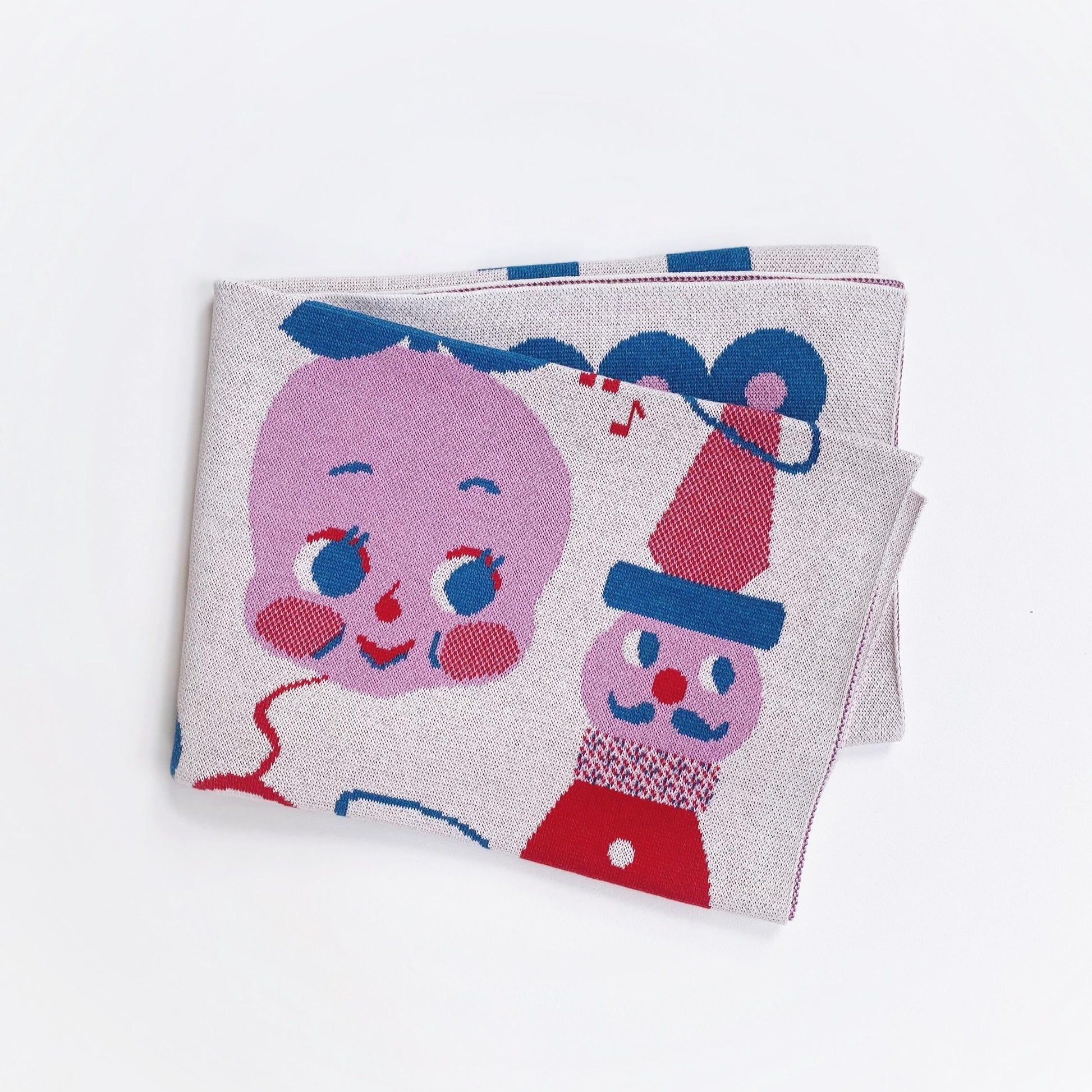 Detail of a folded knit blanket with vintage toy character cartoon design on a white background