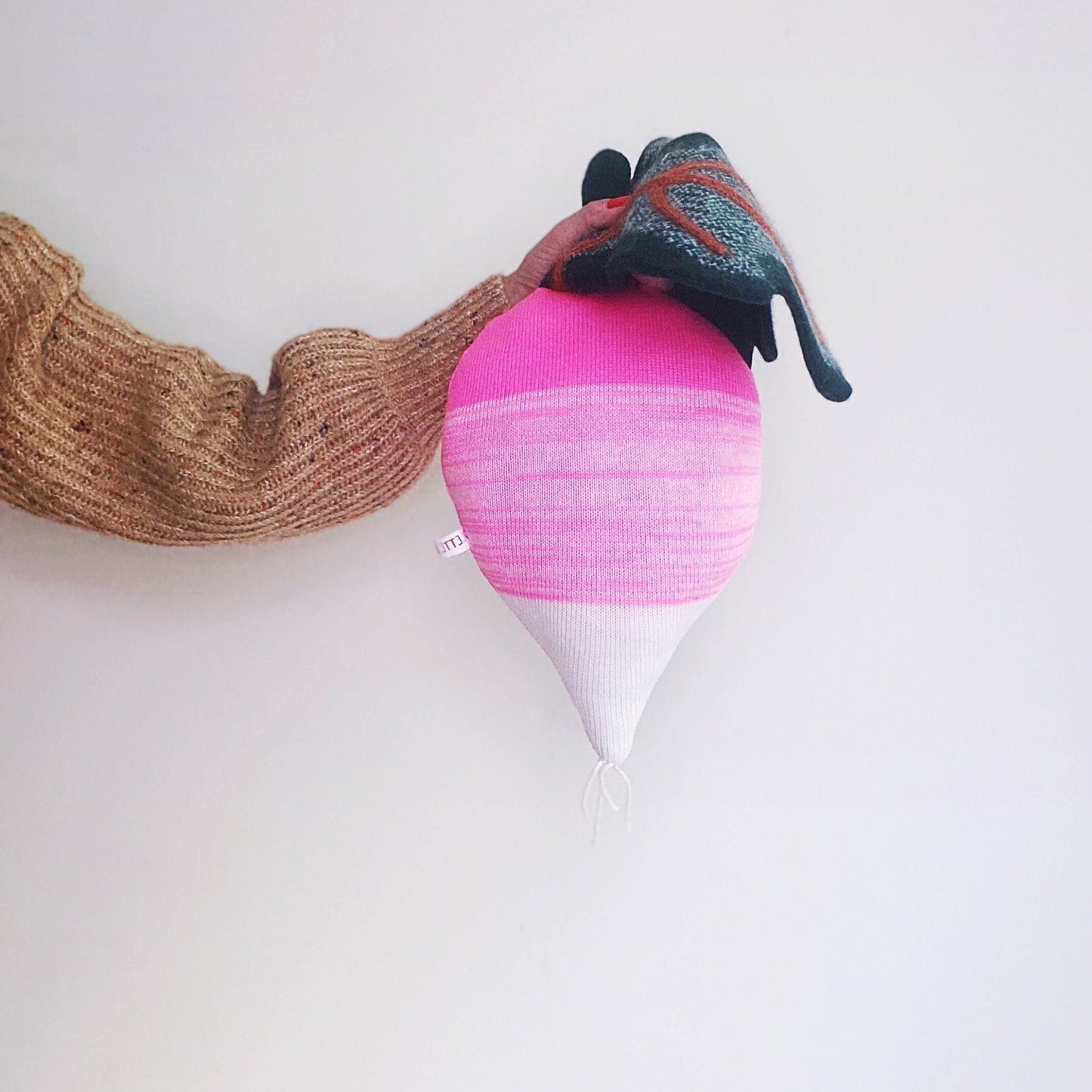 Decorative pink and white radish shaped pillow on a light gray background