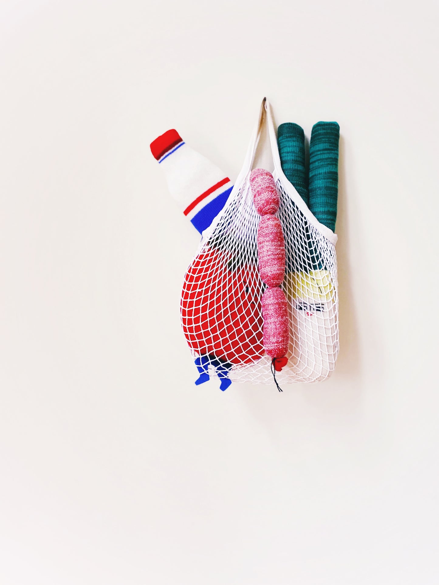 Colorful yarn balls in a mesh bag on a white background