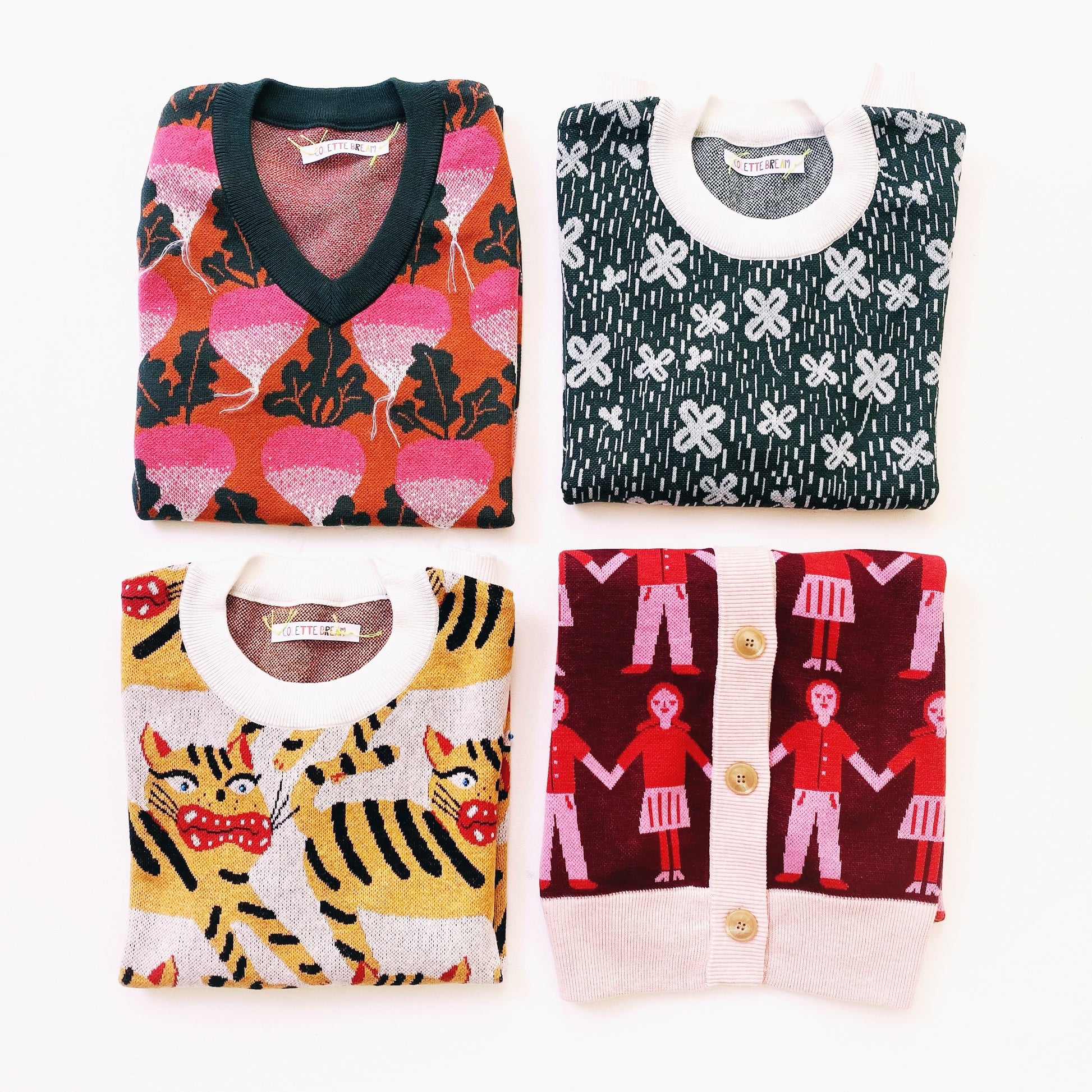 Four folded sweaters with different patterns on a white background