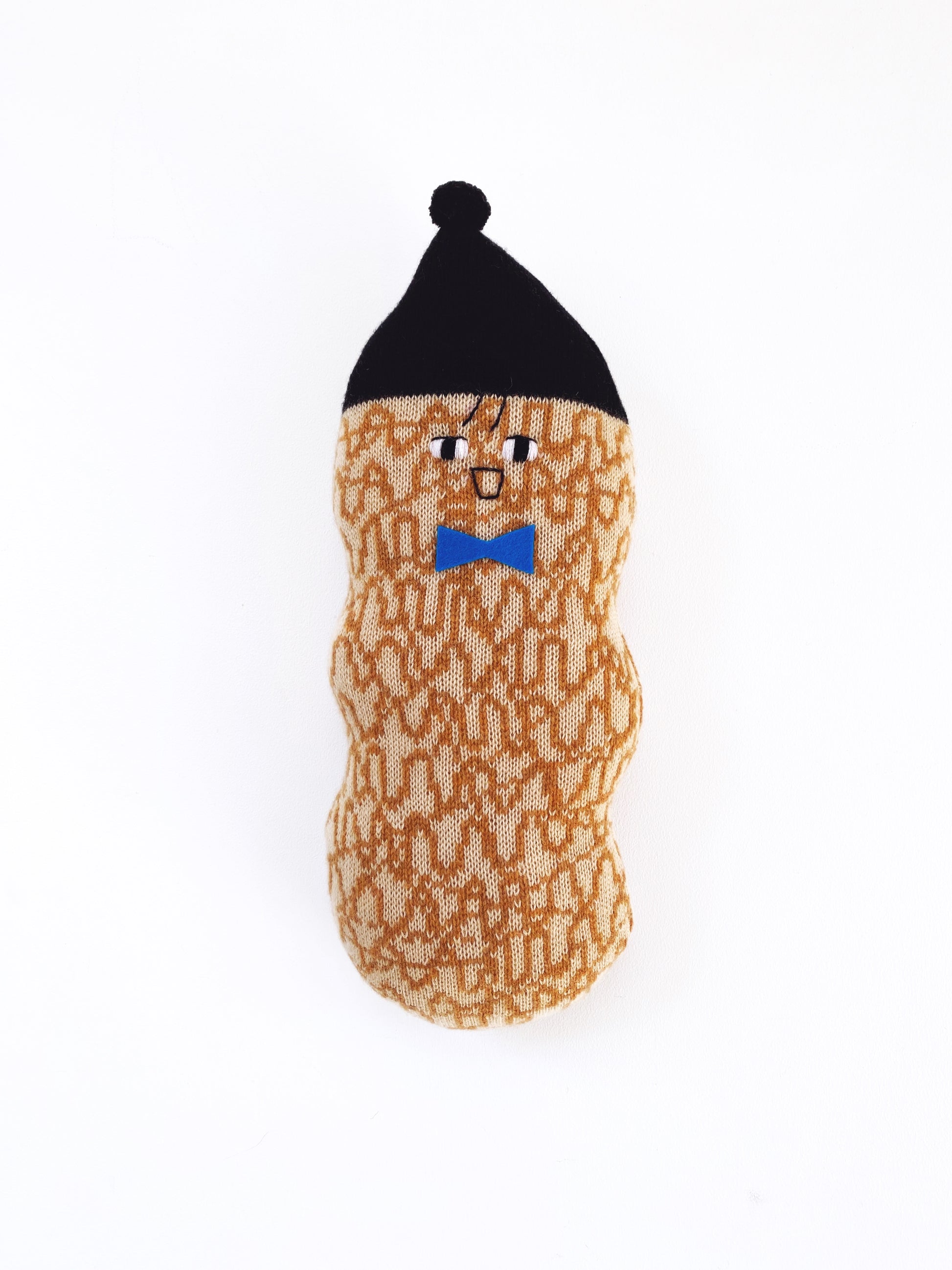 Soft knitted lambswool Toy plush resembling a peanut character with a black hat and blue bow tie on a white background