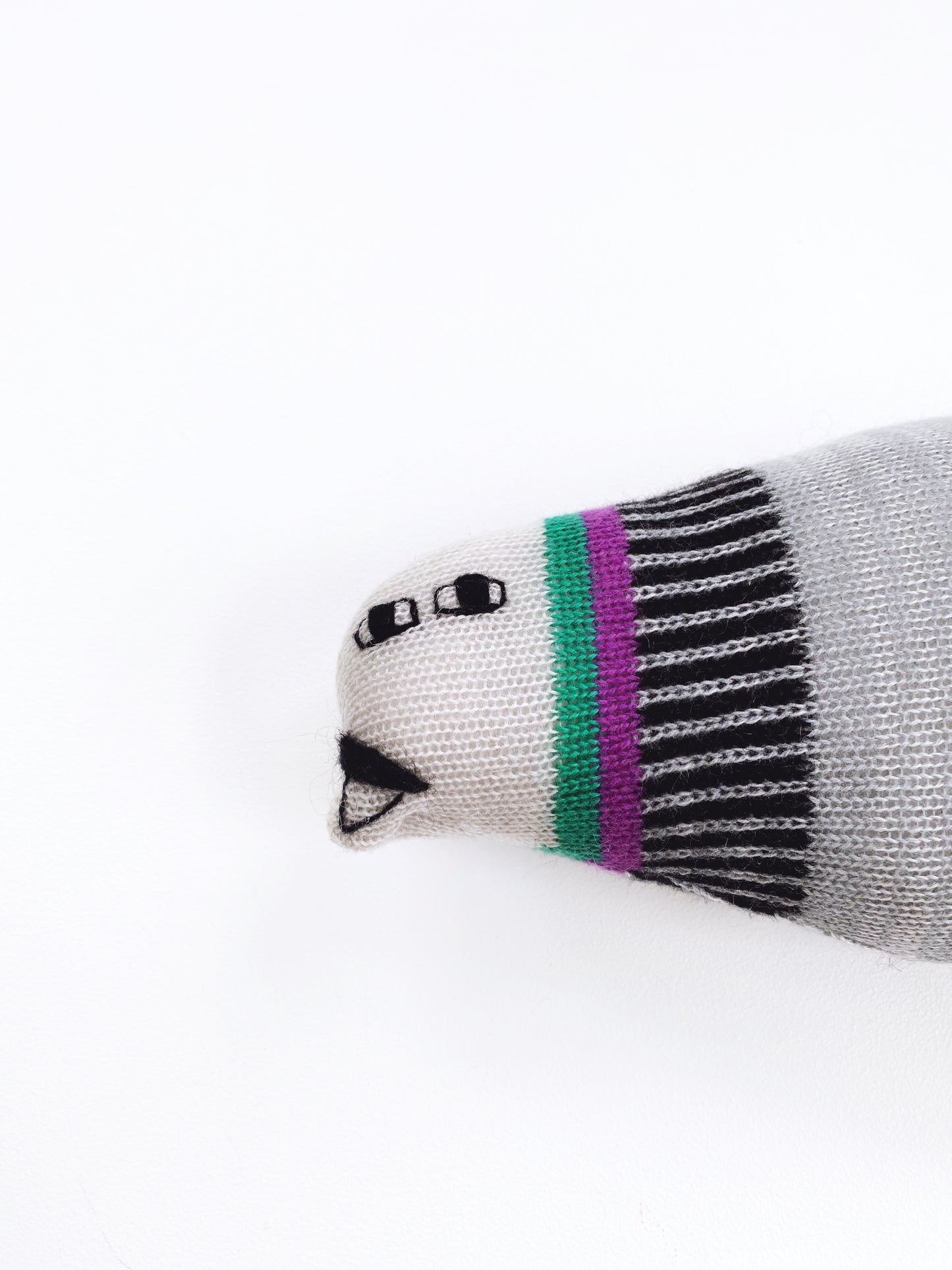 Detail of a soft knitted lambswool pigeon stuffed animal plush on white background