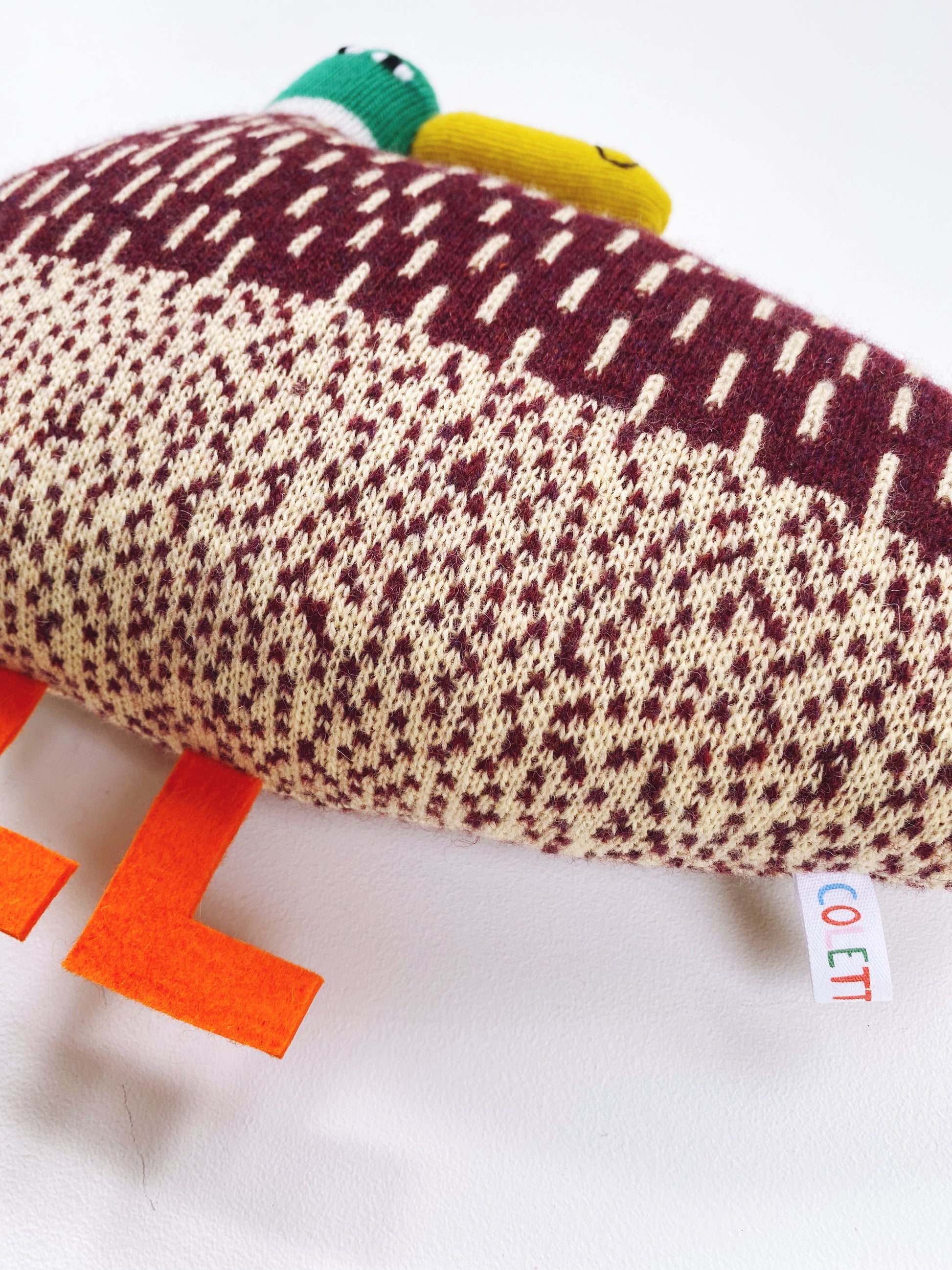 Soft lambswoolKnitted toy duck with colorful accents on a white background