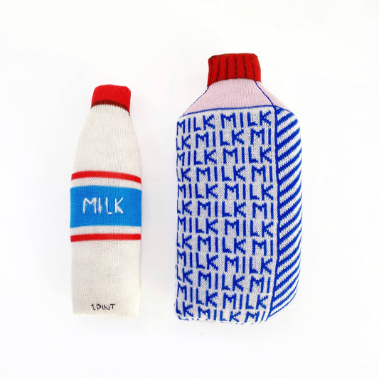 Two knitted milk bottle cushions on a white background