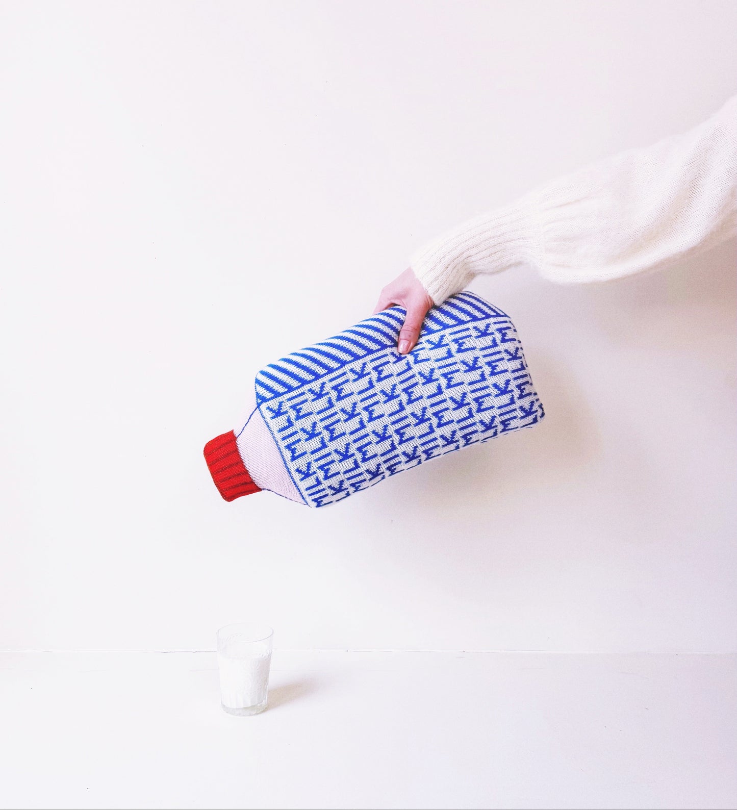 Person holding a blue and white striped pouch over a white bottle with a red cap on a white background