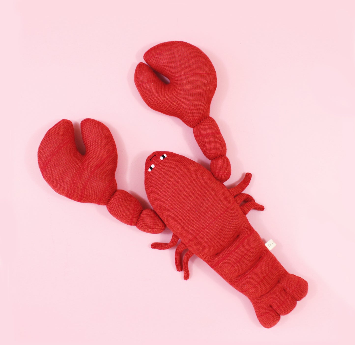 Red lobster plush toy on a pink background