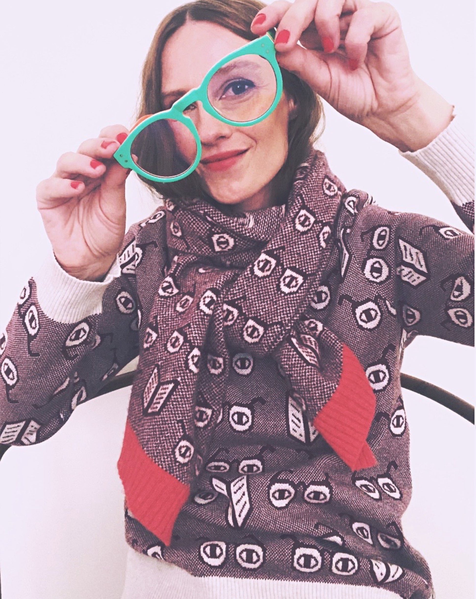 Person wearing a patterned sweater holding green glasses