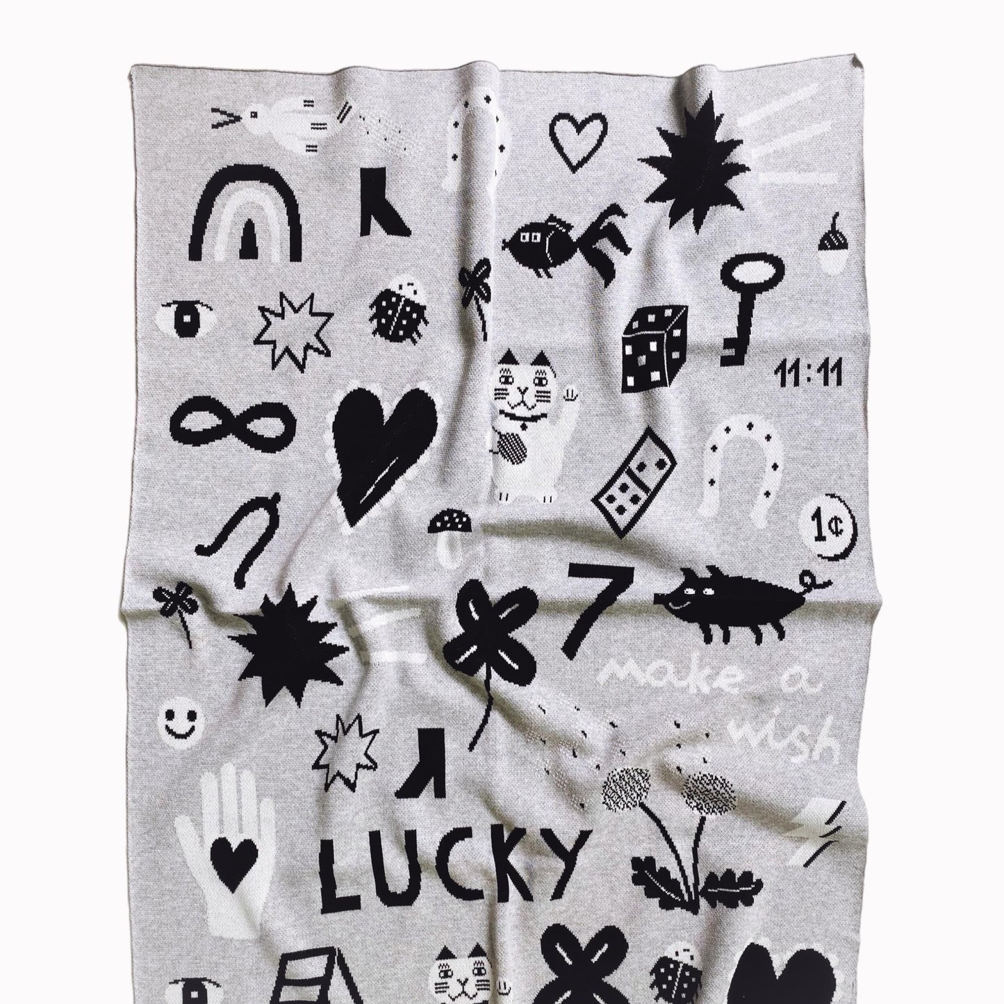 Gray knit blanket with black and white patterns featuring good luck charm designand on a white background