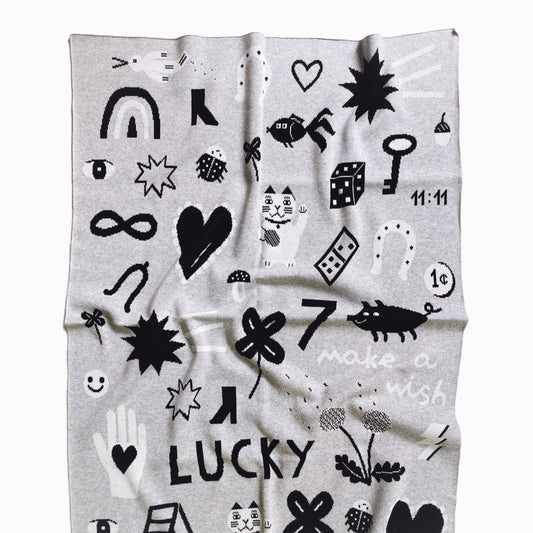 Gray knit blanket with black and white patterns featuring good luck charm designand on a white background