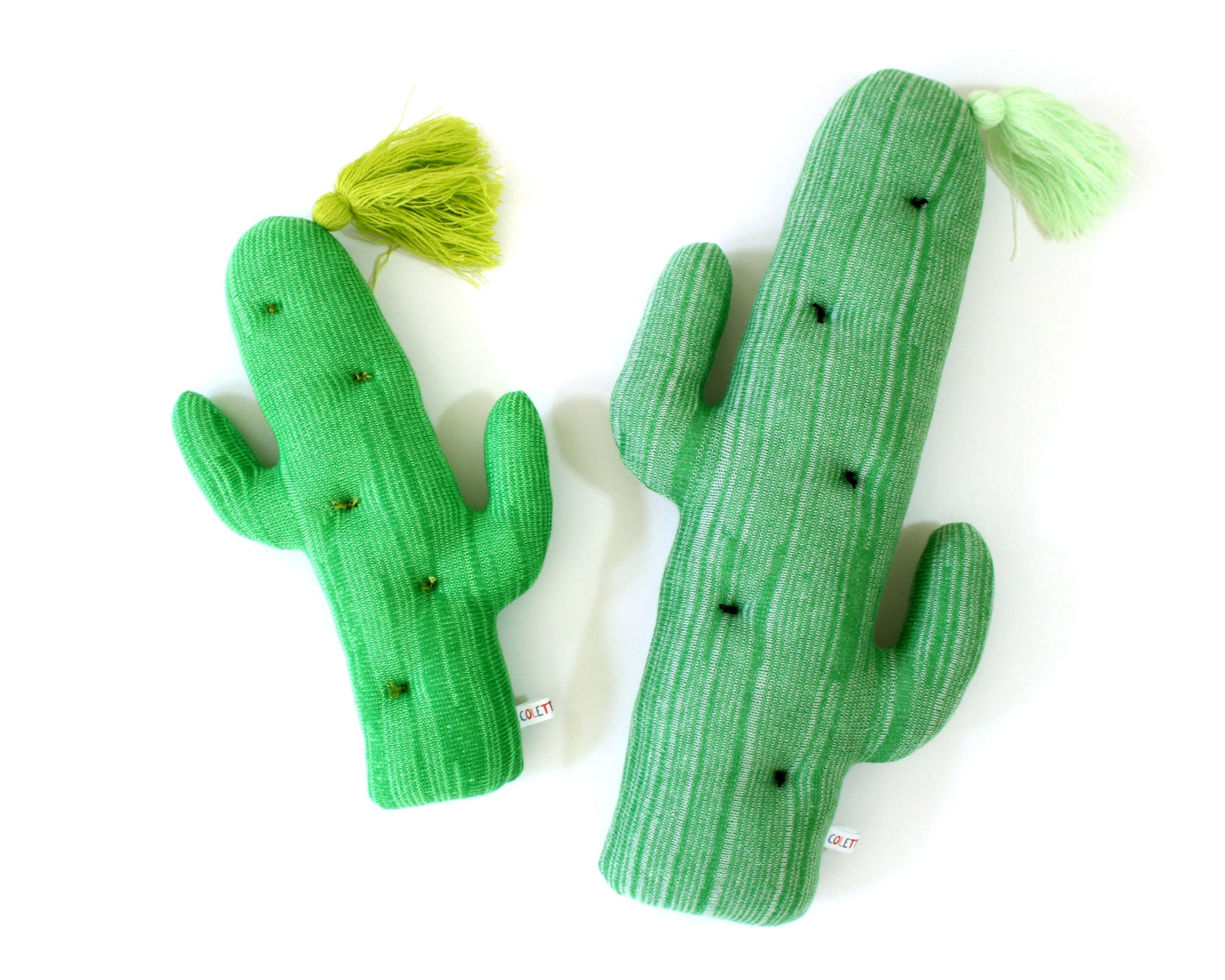 Two green cactus-shaped toys pillows with tassels on a white background