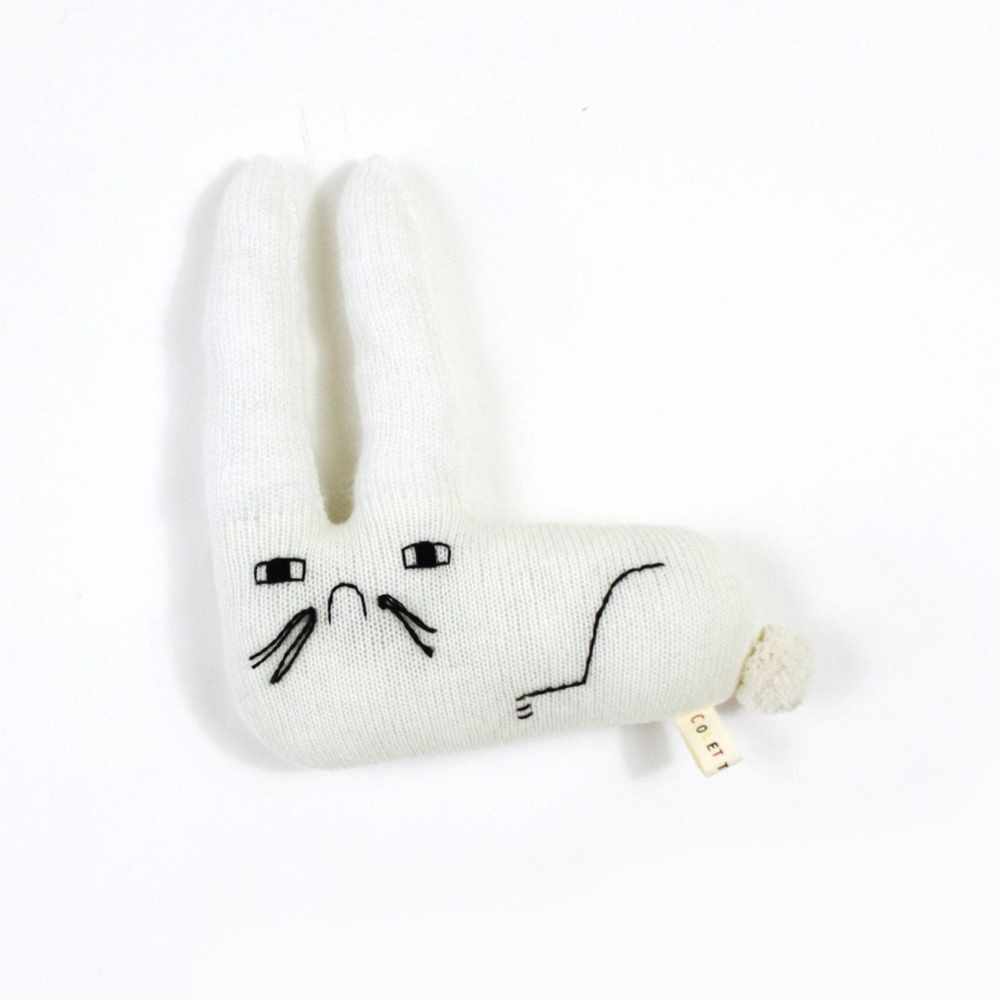 White knitted bunny plush toy with sad face design on a white background