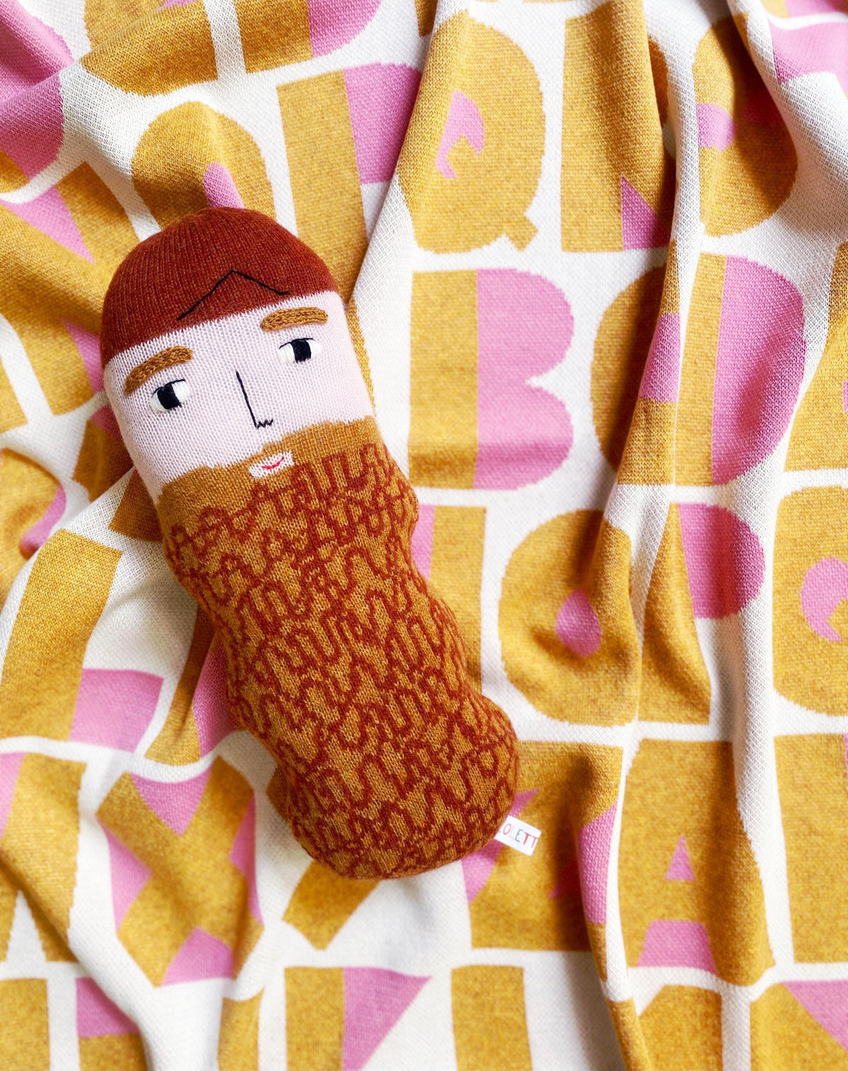 Small plush toy with a face on a colorful patterned fabric background