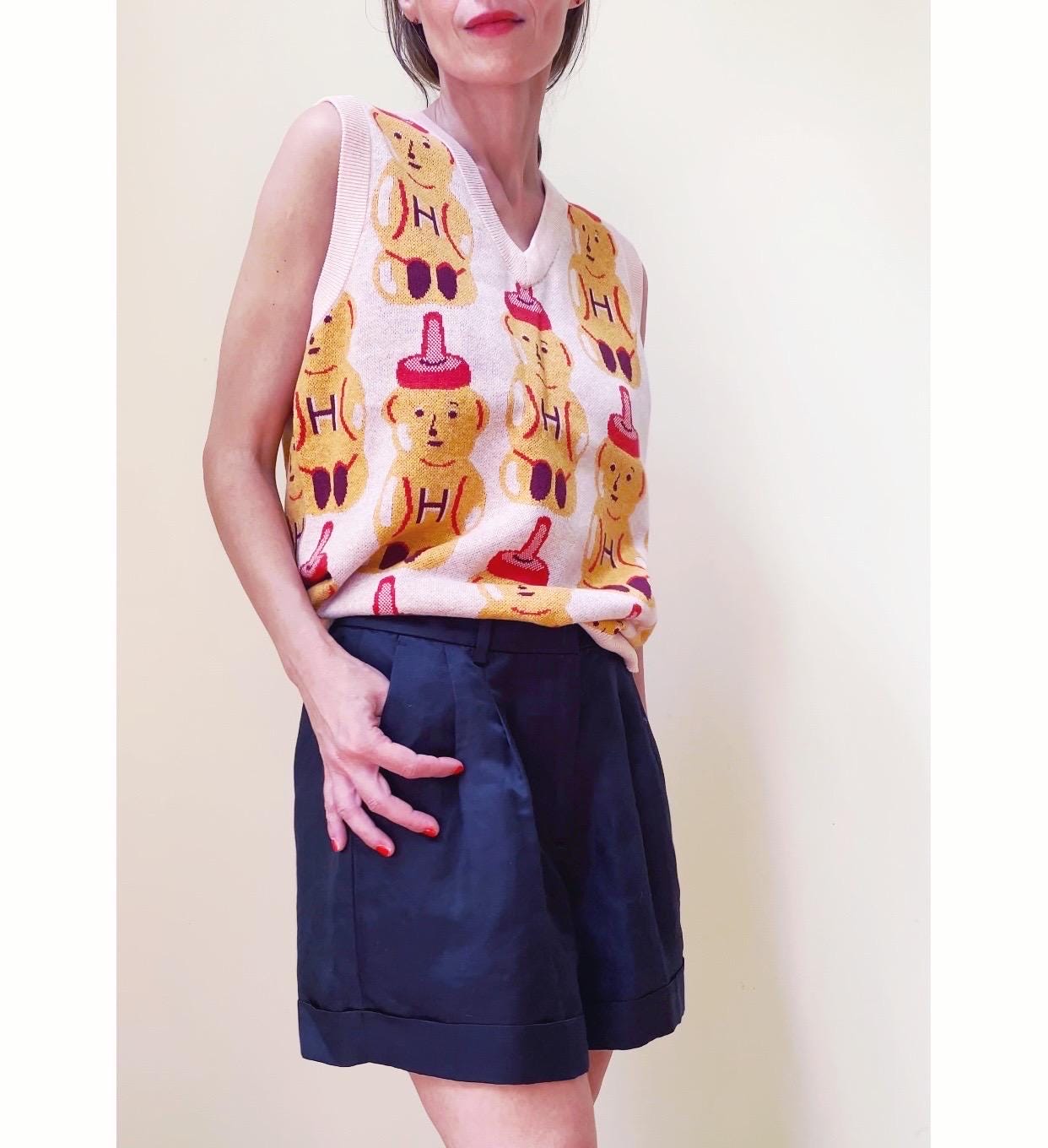 Person wearing a sleeveless top with honey bear pattern and navy shorts against a plain background