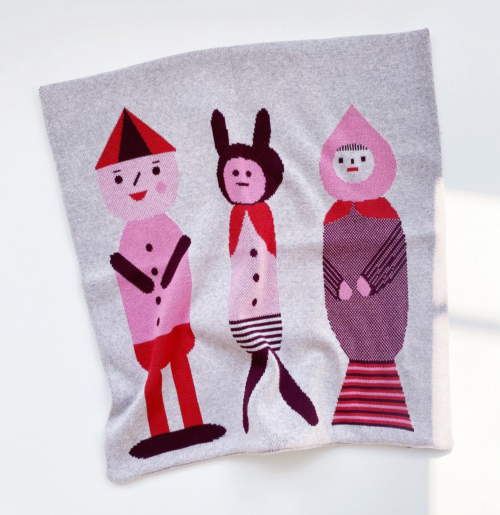 Knitted pillow with colorful cartoon characters on a white background