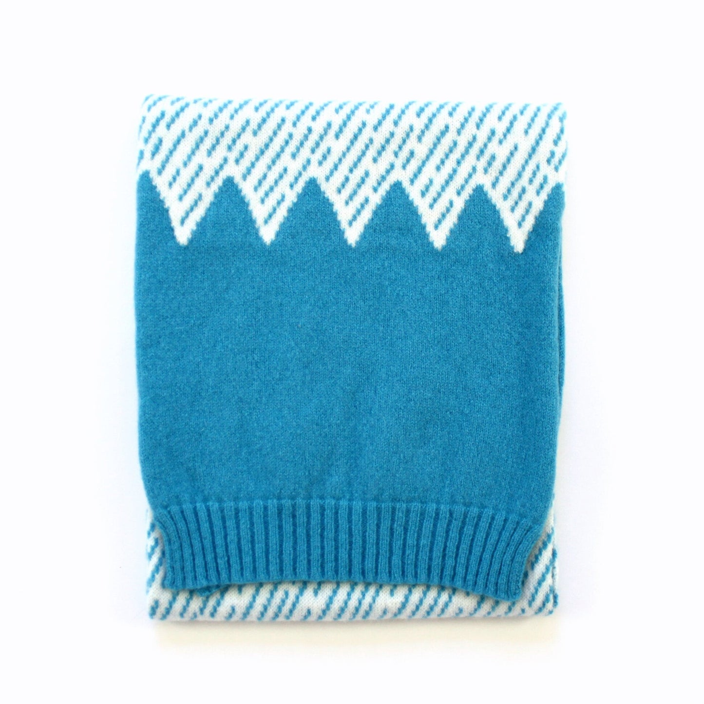 Blue knitted scarf with white mountain pattern on a white background