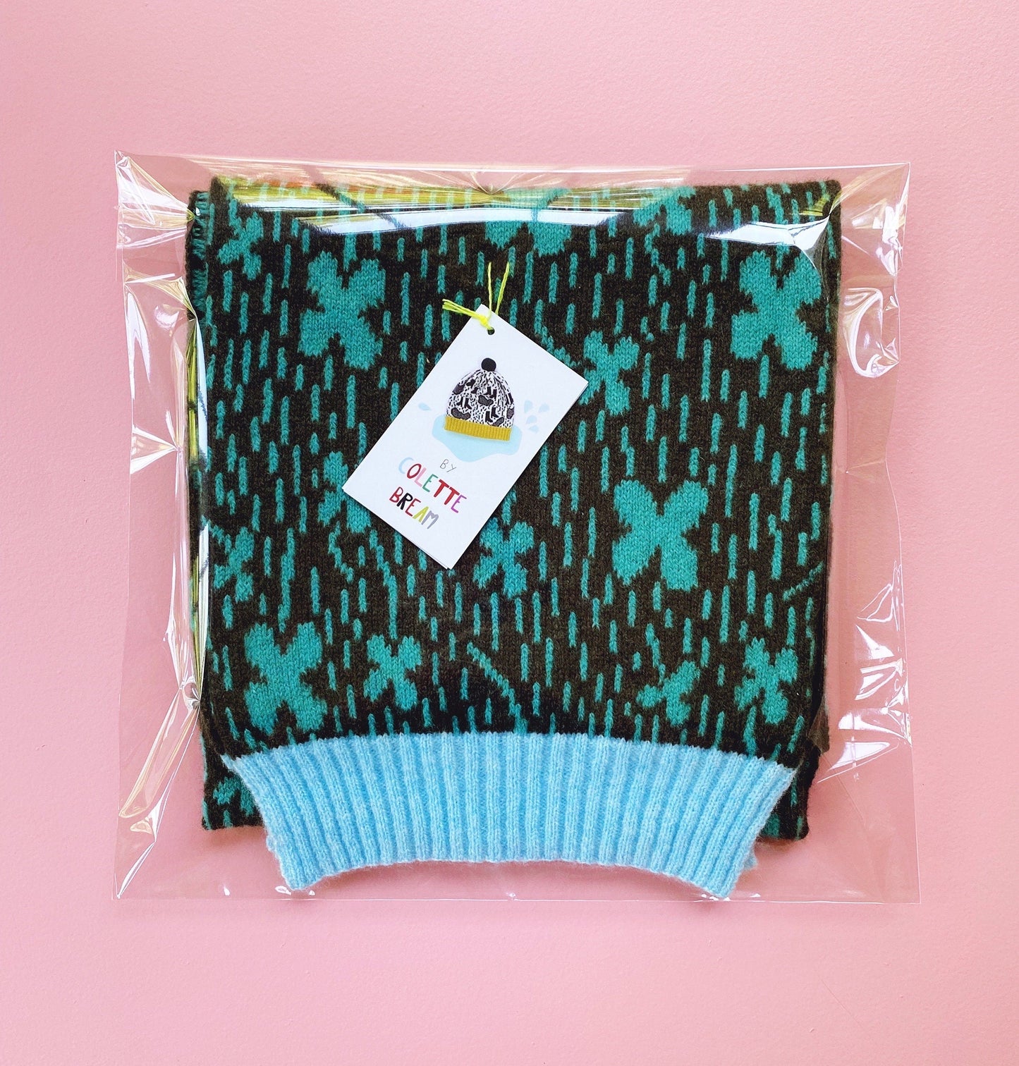 Knitted lambswool scarf with cloverfield pattern in packaging on a pink background