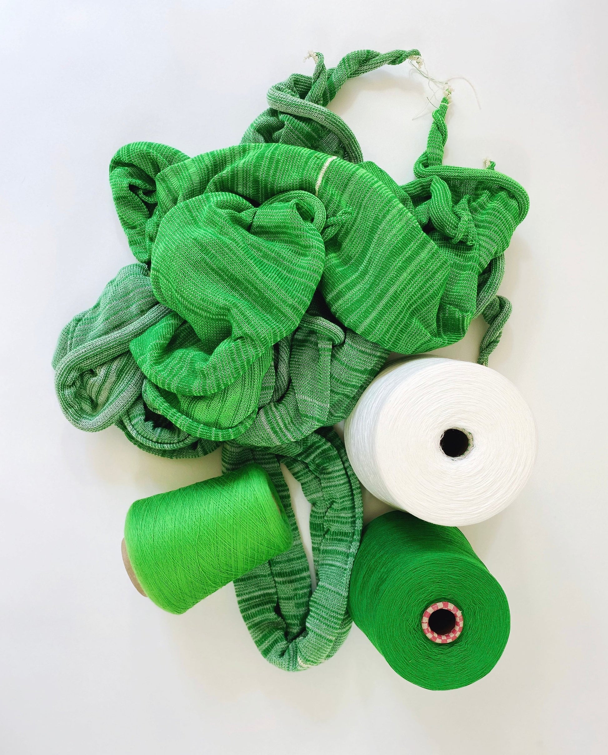 Green fabric and thread spools on a white background