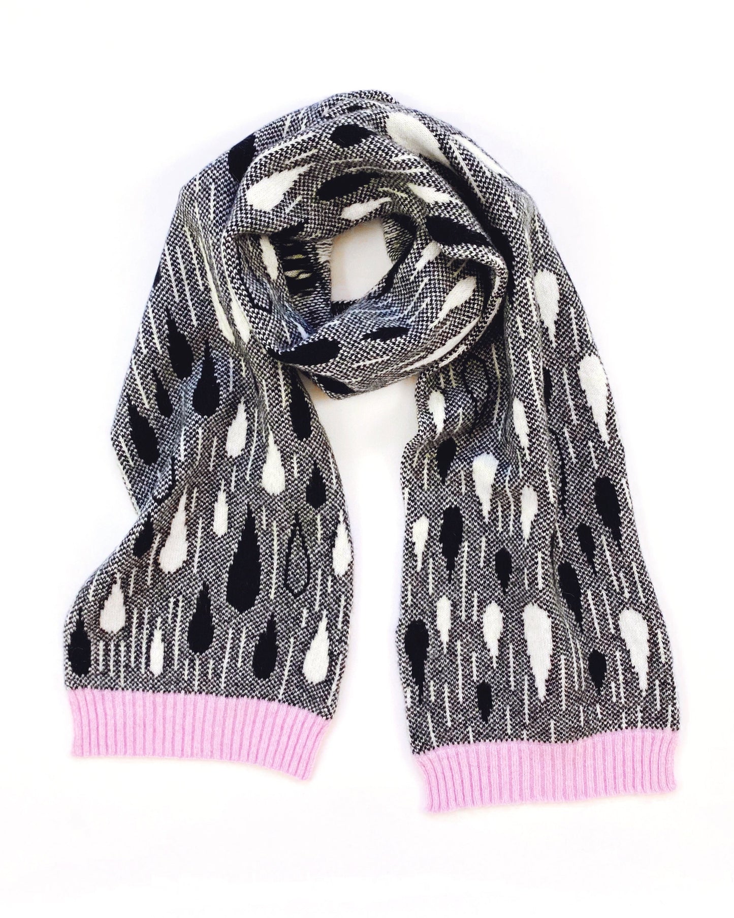 Knitted lambswool scarf with black and white raindrop pattern and a pink trim on a white background