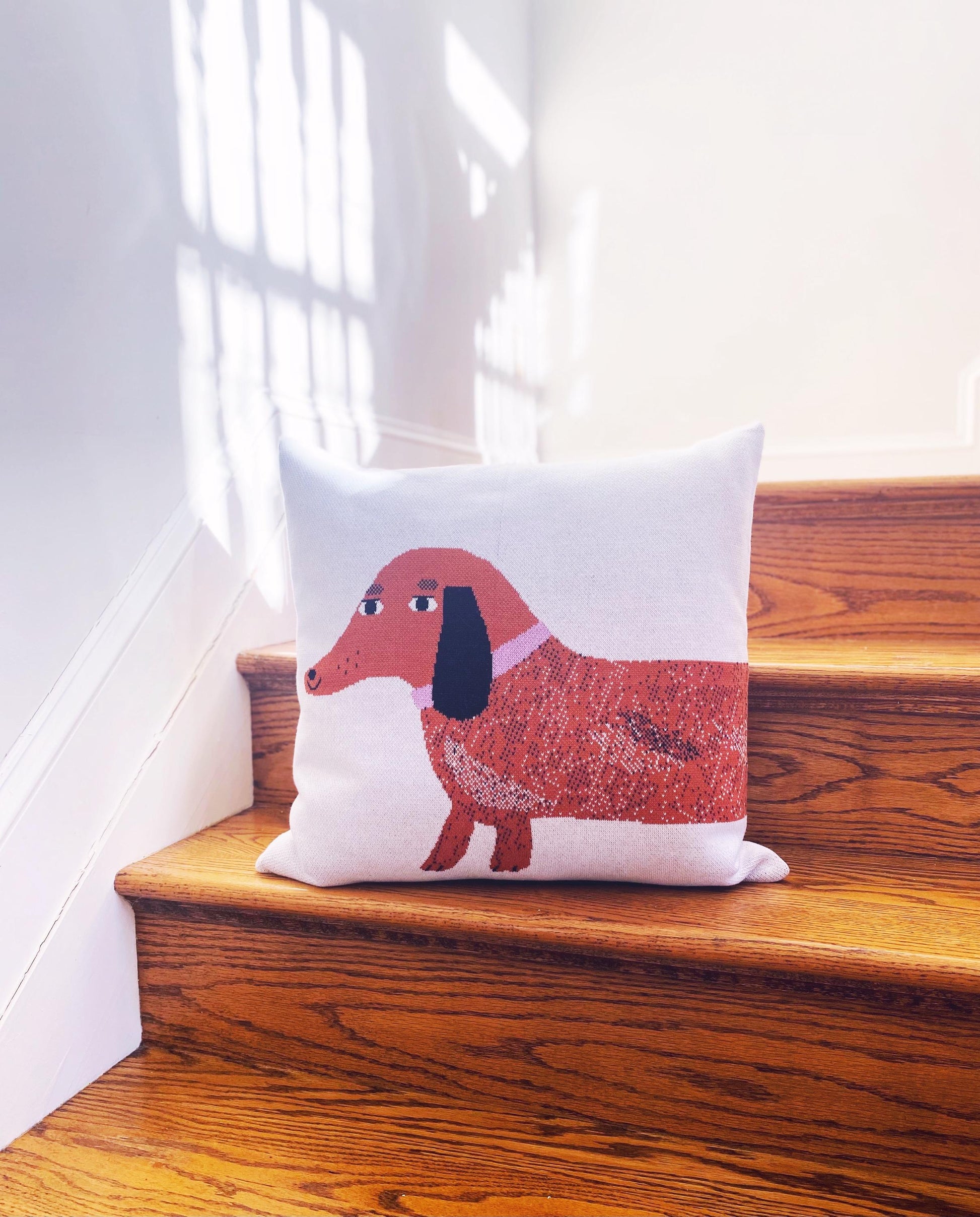 Knitted pillow with a dachshund dog design on wooden stairs