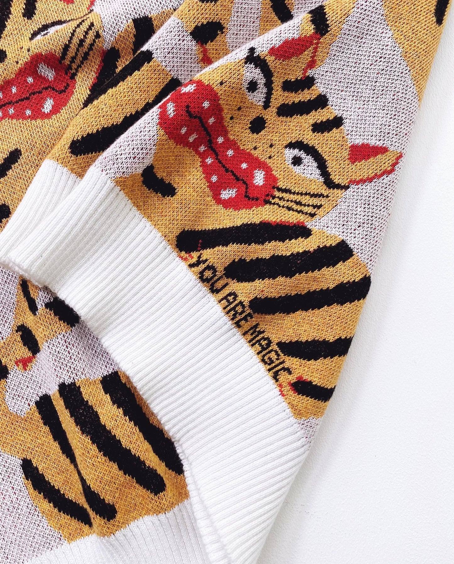 Detail of a knitted sweater with Hariko Tora tiger design and text on a white background