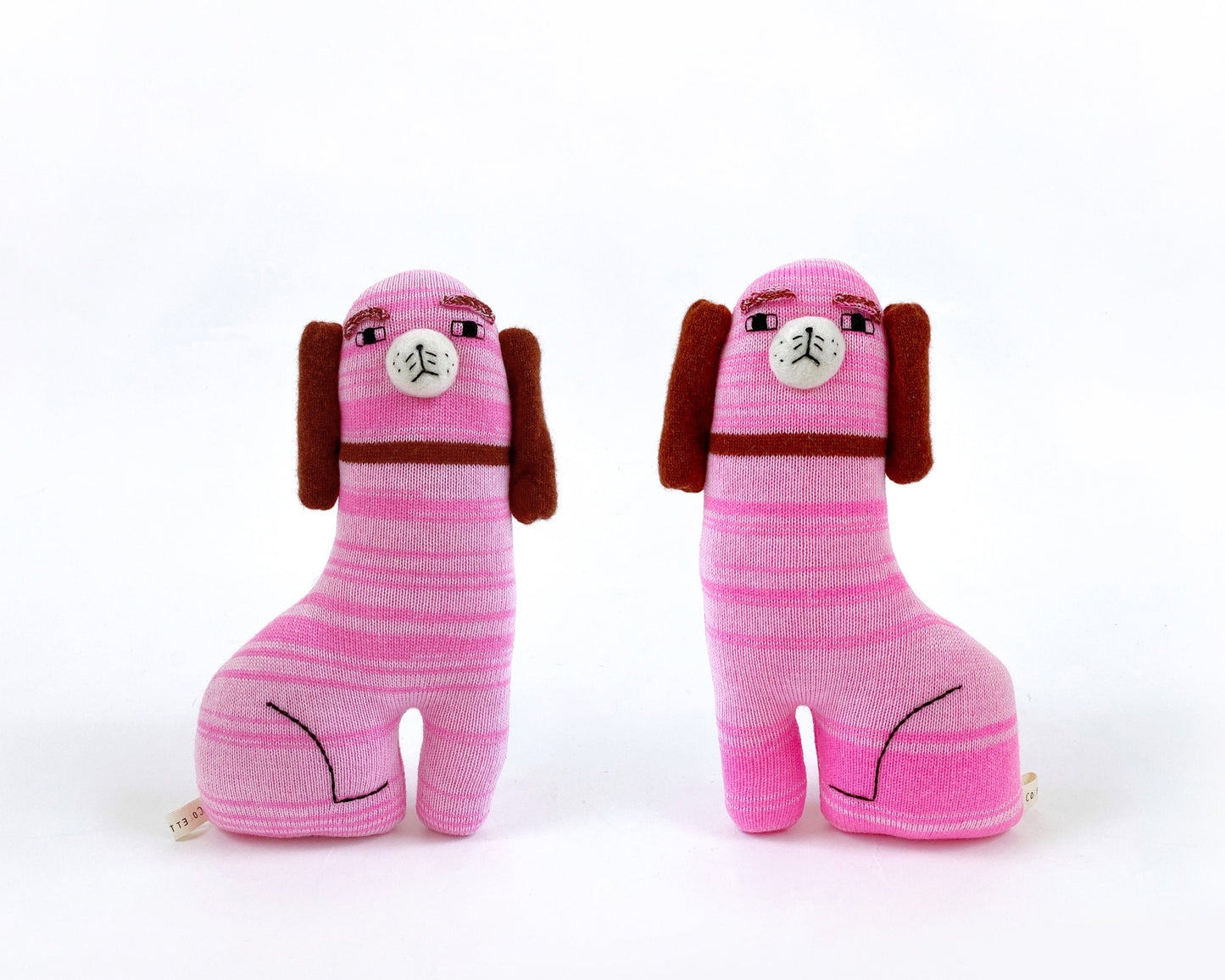 Two pink striped knitted staffordshire dog toy figures with brown ears on a white background