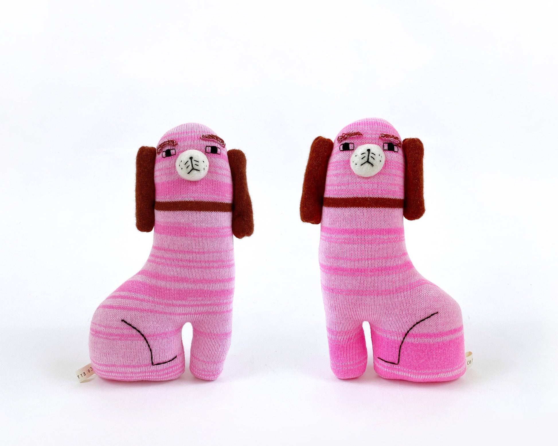 Two pink striped knitted staffordshire dog toy figures with brown ears on a white background