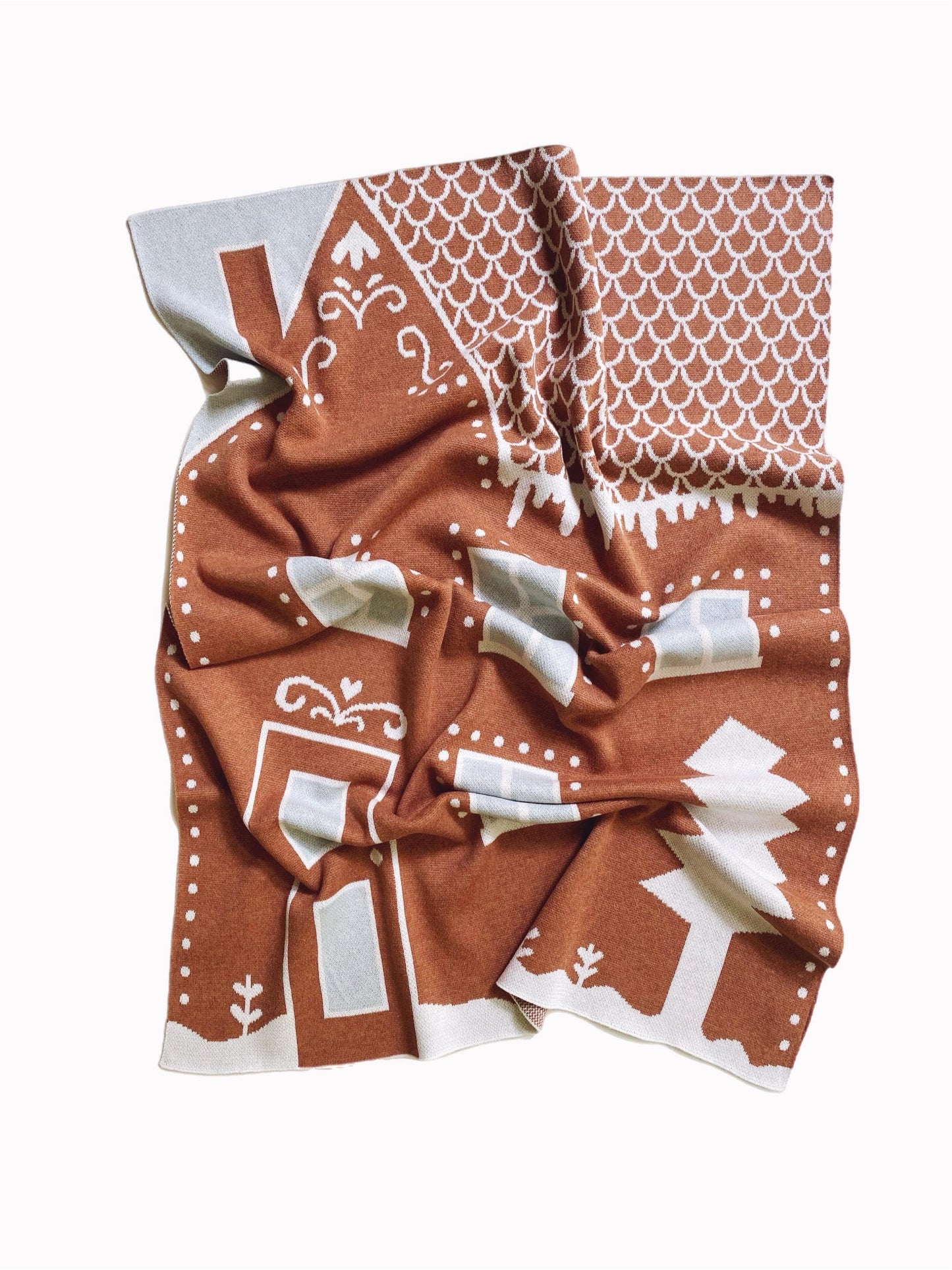 Folded knitted fabric with brown and white gingerbread house pattern design on a white background