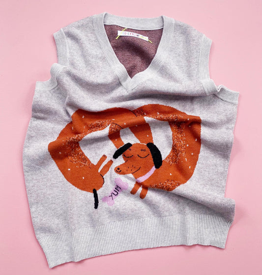 Gray sleeveless sweater with cartoon sausage dog design on a pink background