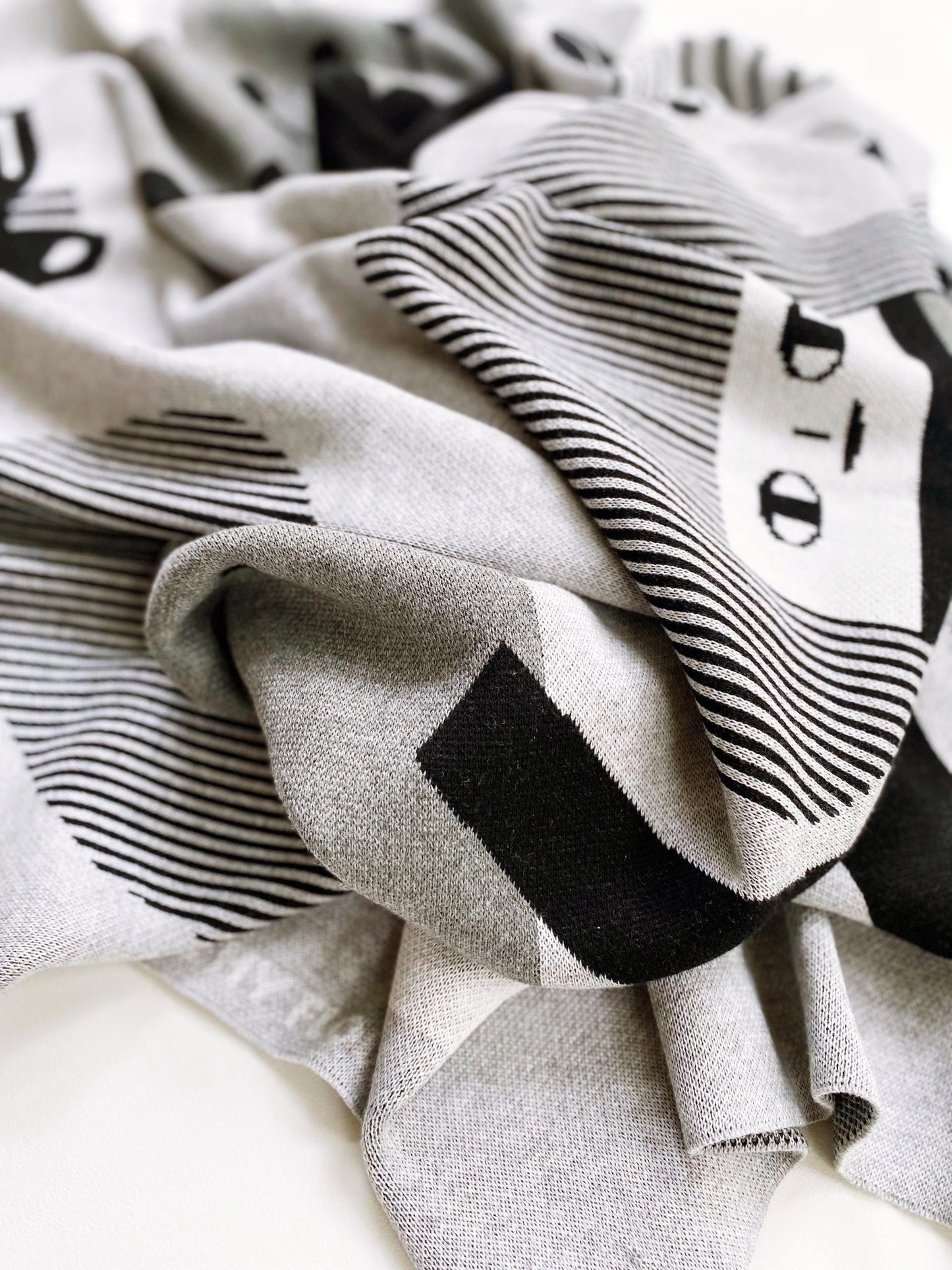 Close-up of a knitted fabric with black geometric patterns on a neutral background