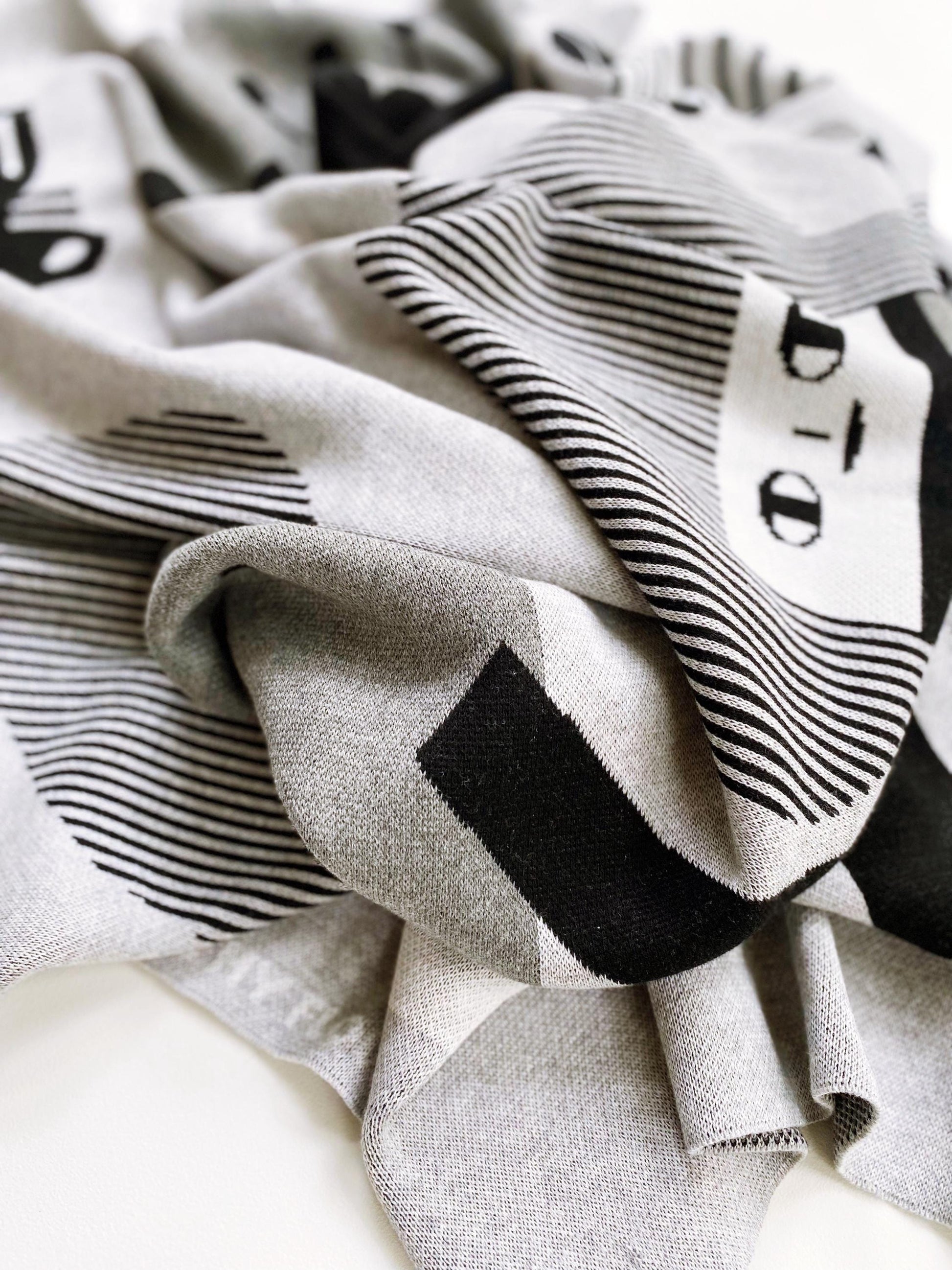 Close-up of a knitted fabric with black geometric patterns on a neutral background