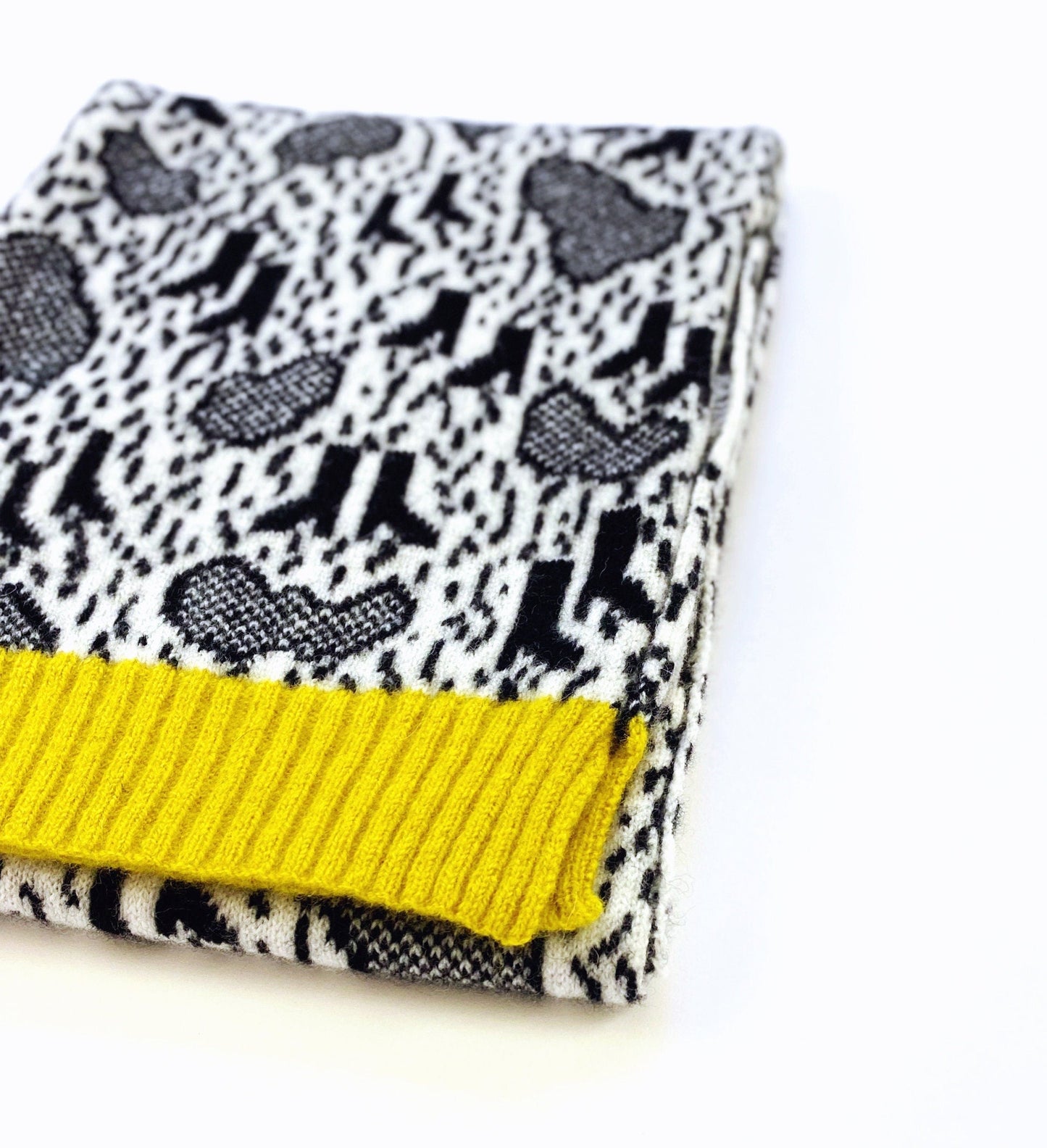 Folded lambswool scarf with black and white pattern and yellow trim on a white background